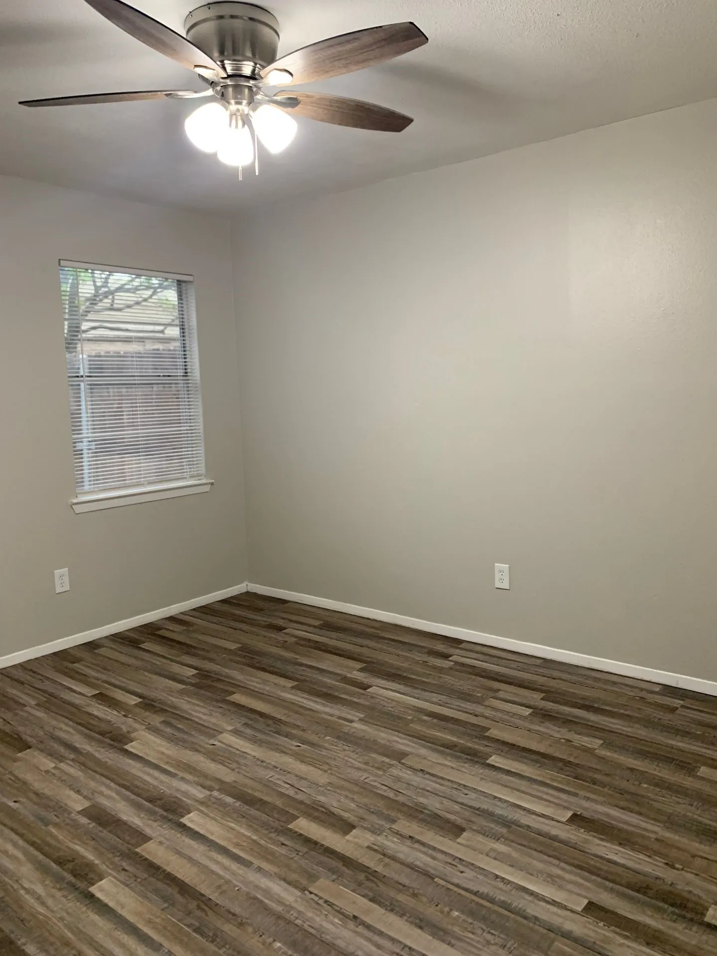 Wood-finish flooring, neutral wall tones, and a window with blinds