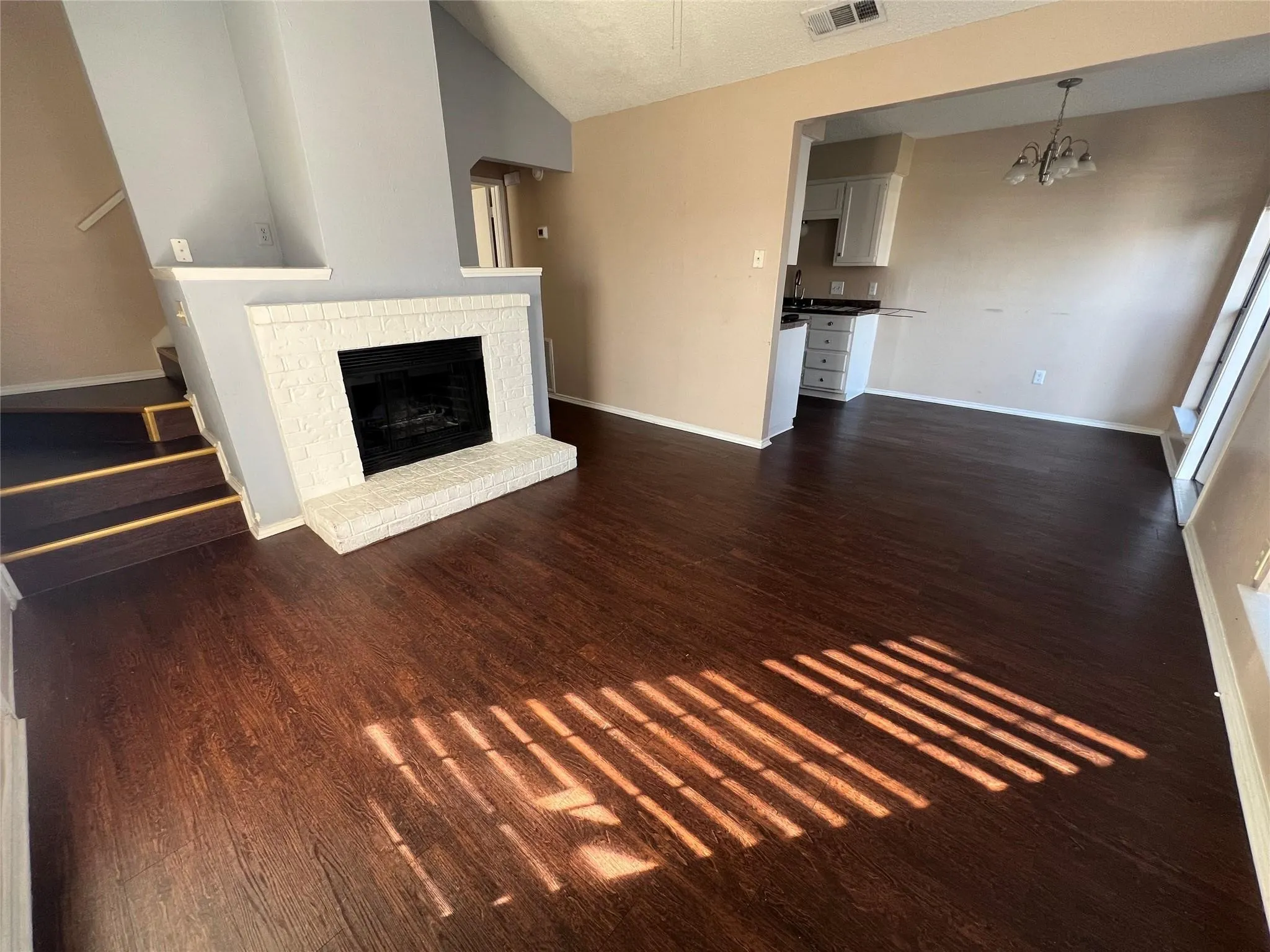 Wood-finish flooring throughout, white painted brick fireplace, vaulted ceiling, and an open concept layout