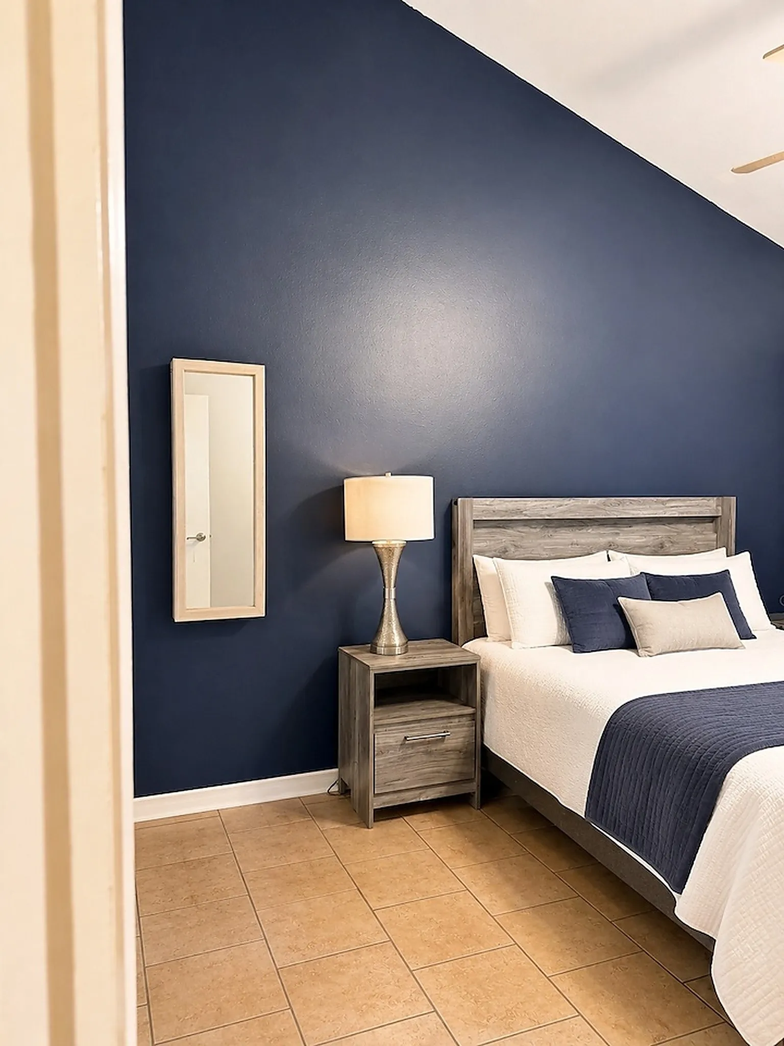 Vaulted ceiling with an attached ceiling fan, tile flooring, and a neutral-toned baseboard