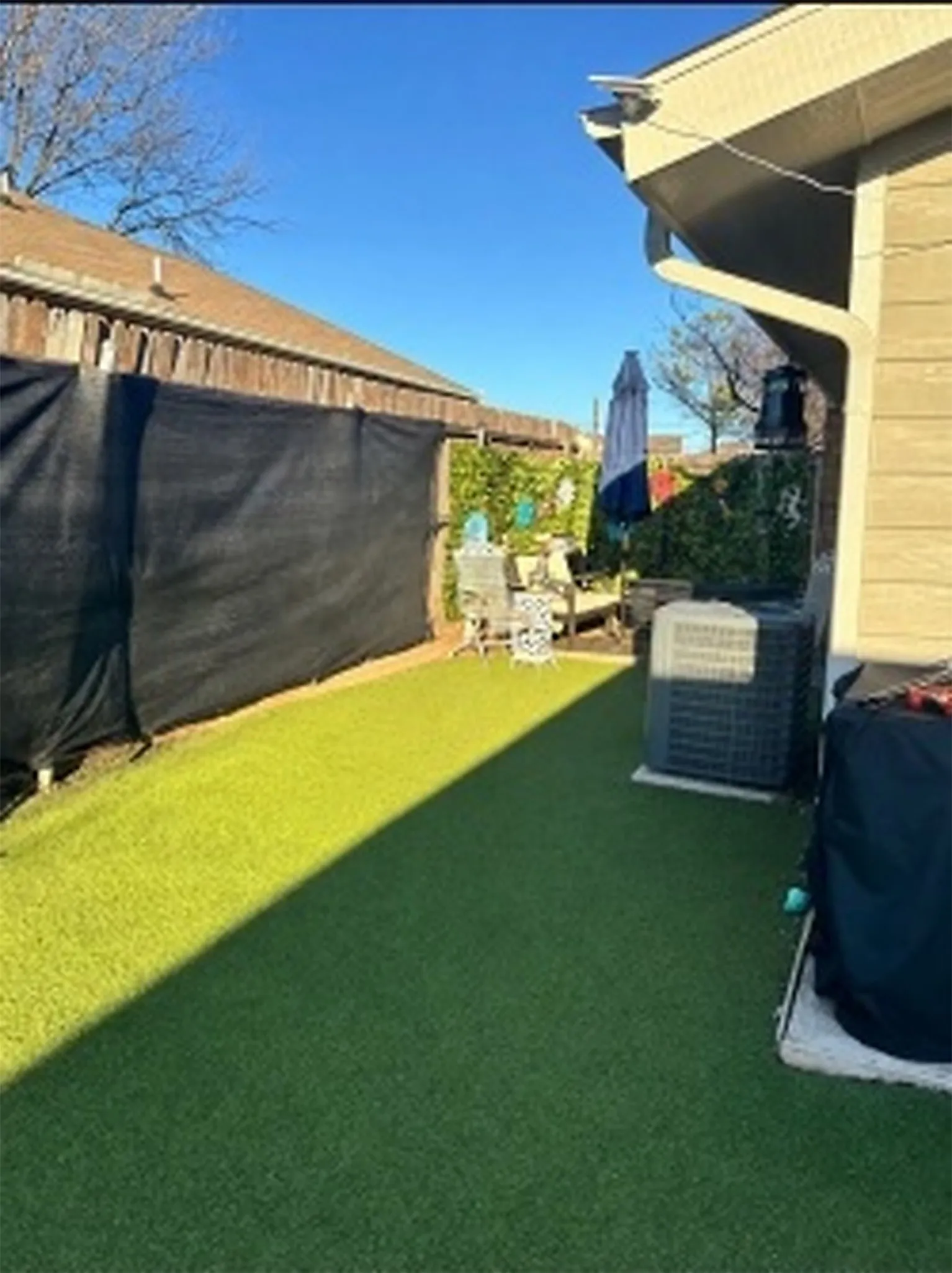 Landscaped side yard featuring artificial turf and wood fencing