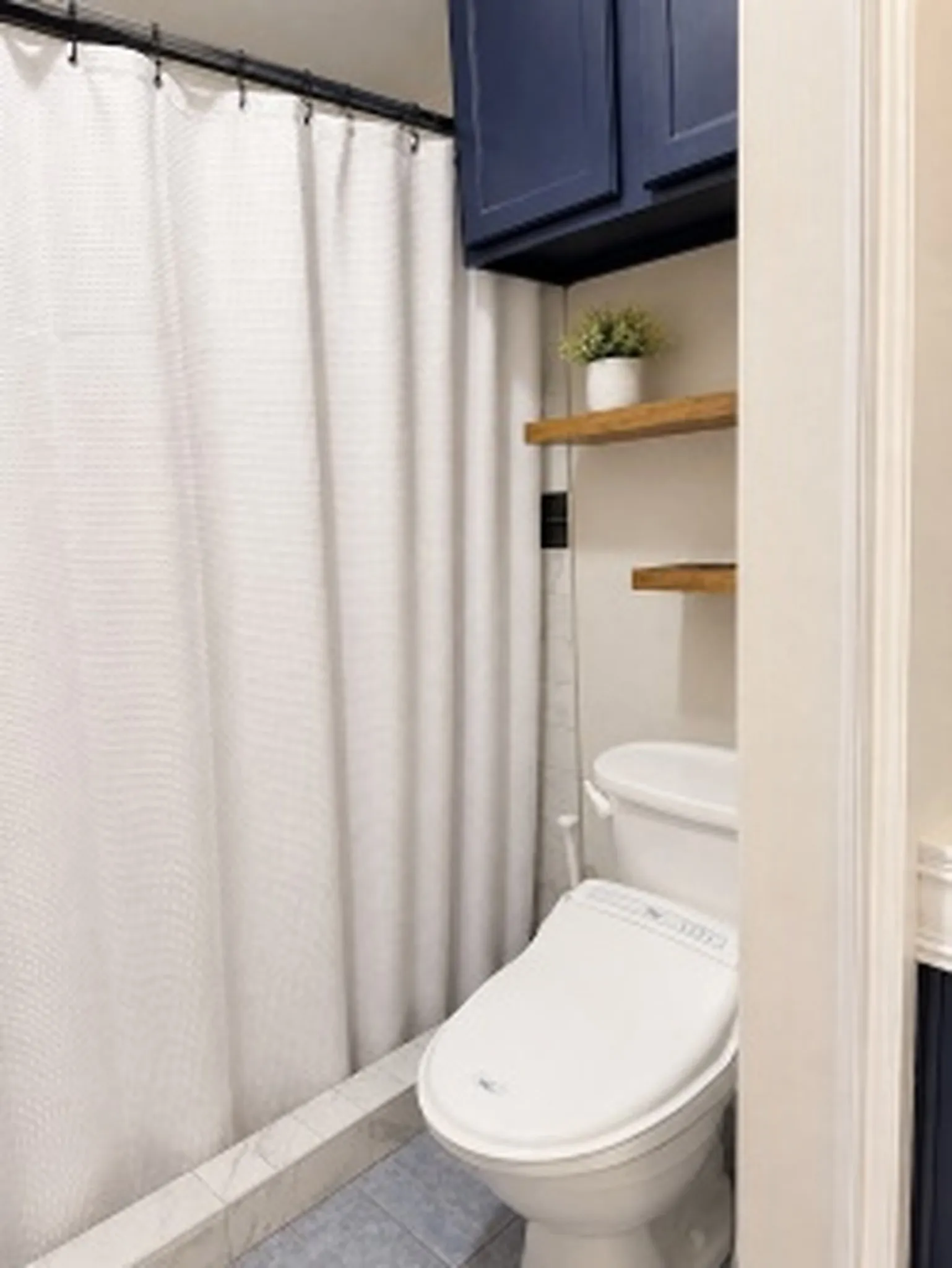 Guest - Built-in blue cabinetry, wood-finish floating shelves, and a modern toilet