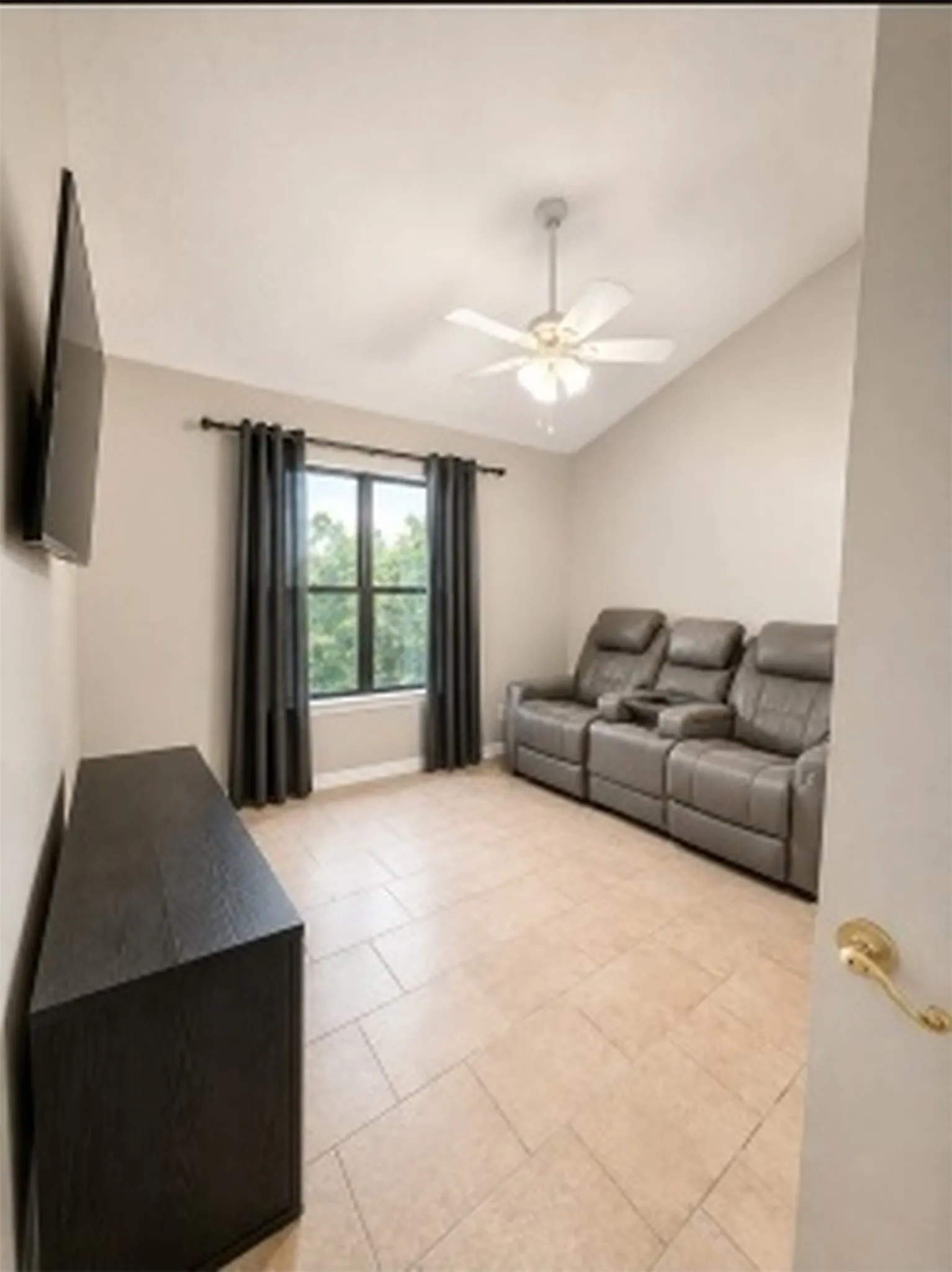 Vaulted ceiling featuring a ceiling fan, tiled flooring, and a large window