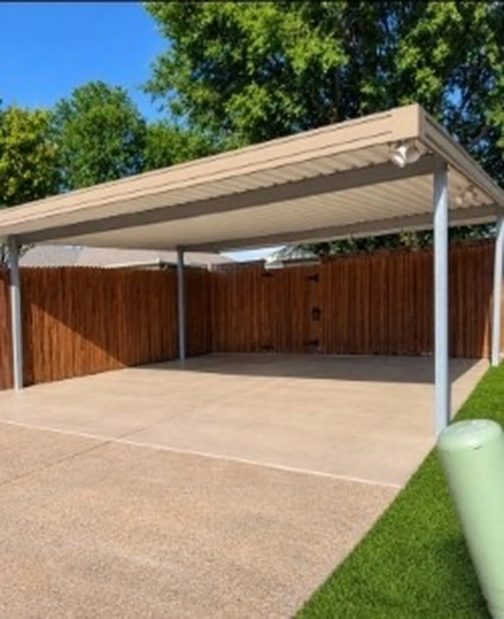 Covered carport featuring a concrete pad, metal roof, and supporting posts