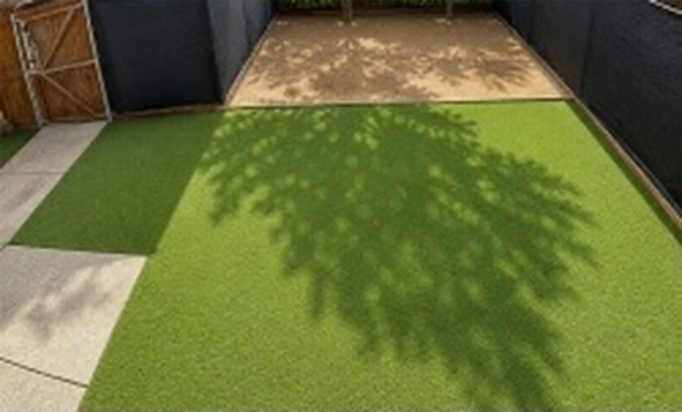 Artificial turf, natural ground cover, concrete paving, and wood-paneled fencing