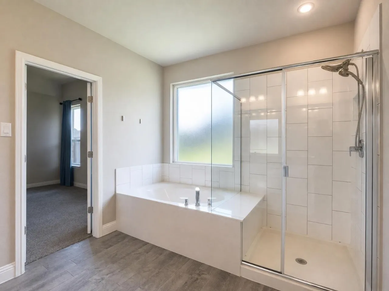 Tiled soaking tub, glass-enclosed shower with subway tile surround, recessed lighting, and wood-finish flooring