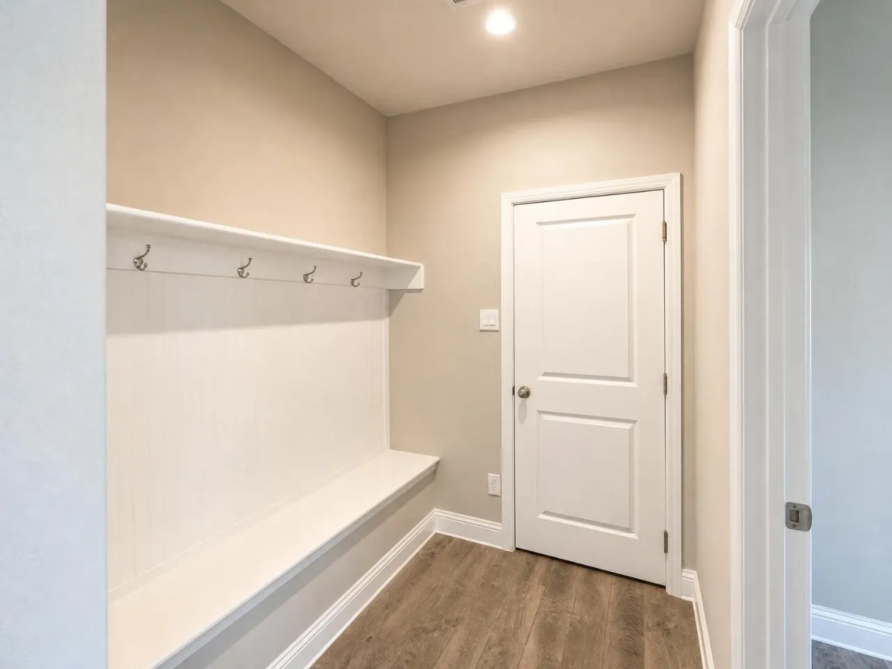 Built-in bench and shelving with integrated hooks, recessed lighting, and wood-finish flooring