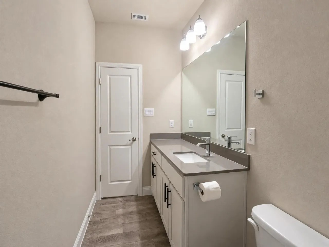 Single vanity with a light gray countertop, undermount sink, chrome faucet, and integrated mirror