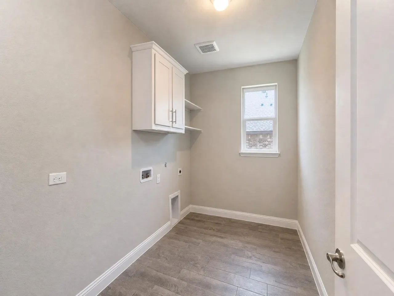 Tile flooring, built-in cabinetry, shelving, window, and wall-mounted light fixture