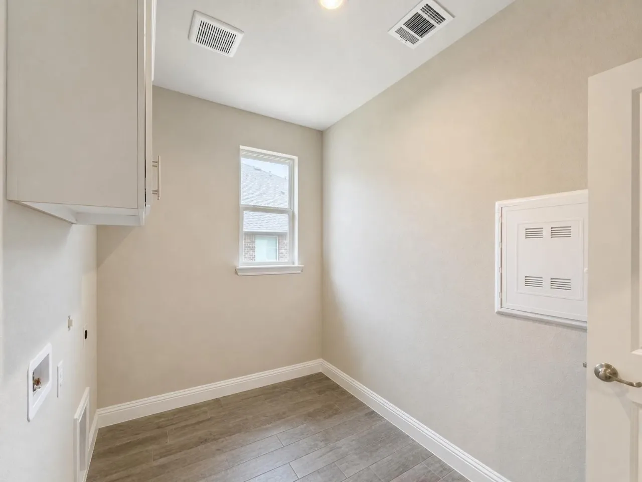 Upper cabinetry, single window, wood-finish flooring, and white trim