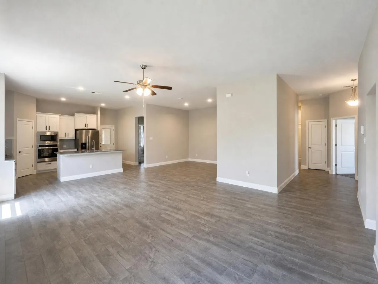 Open concept living area featuring wood-finish flooring, recessed lighting, a ceiling fan, and a kitchen island with seating