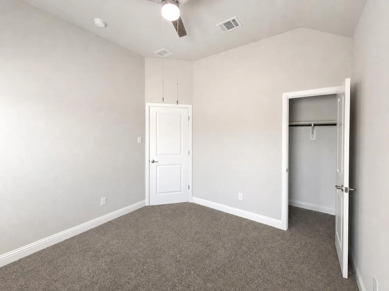 Vaulted ceiling with an attached ceiling fan, neutral wall paint, gray carpet flooring, white trim, and a closet with a hanging rod