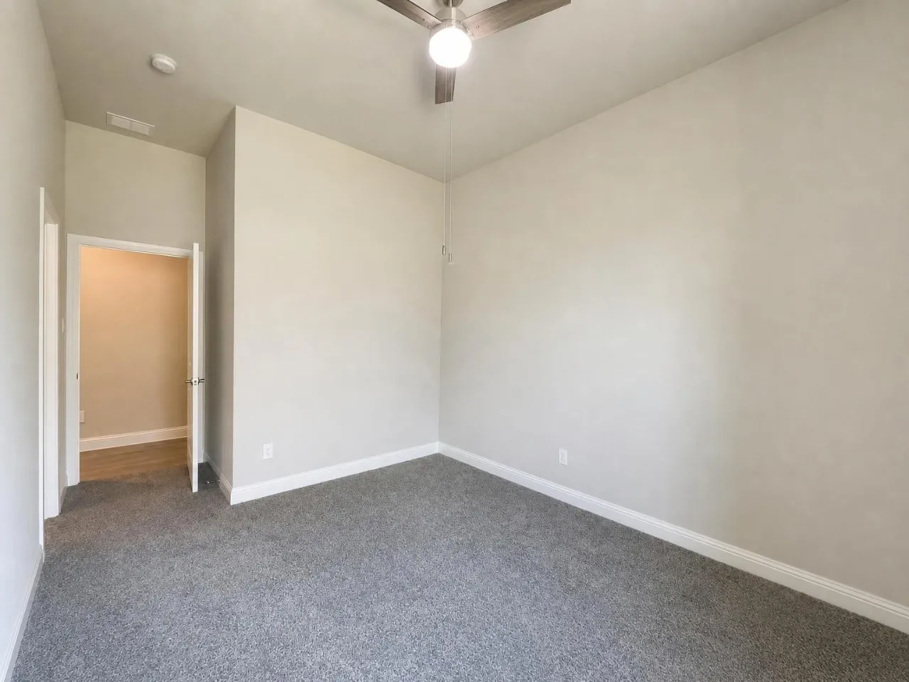 Neutral wall paint, ceiling fan with light fixture, gray carpet, and white trim
