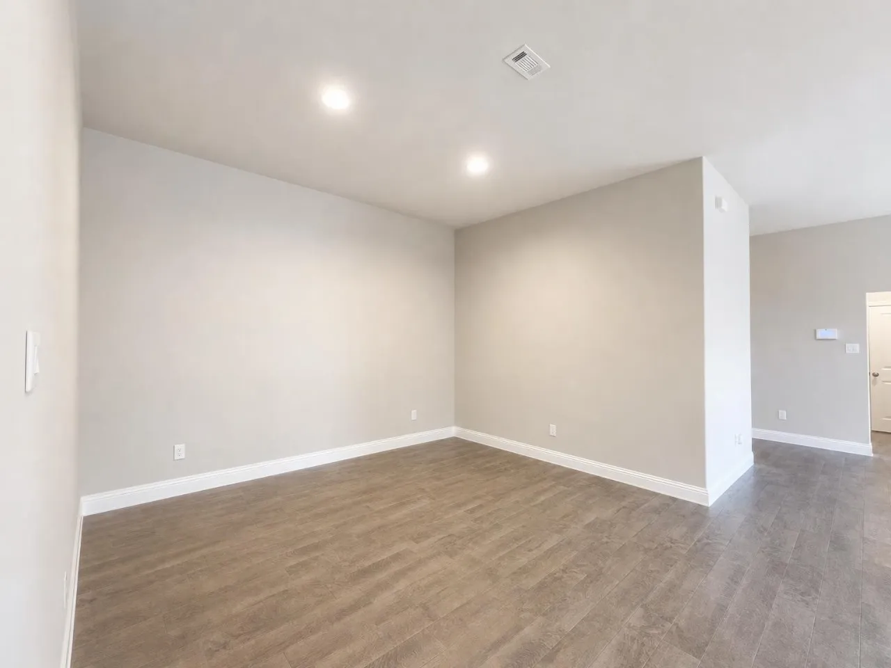 Recessed lighting, wood-finish flooring, light-toned wall paint, and white trim