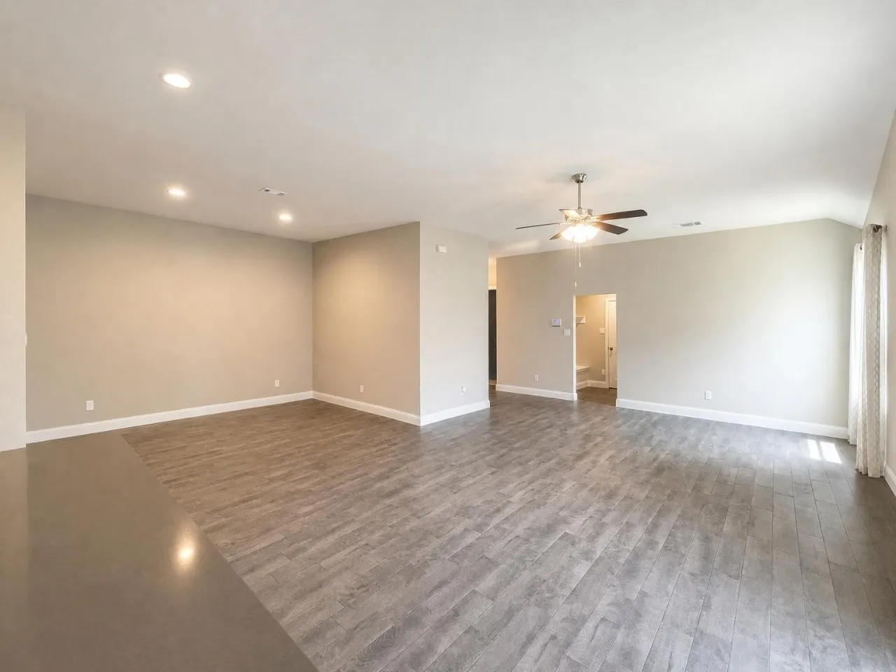 Spacious room featuring wood-finish flooring, recessed lighting, and a ceiling fan