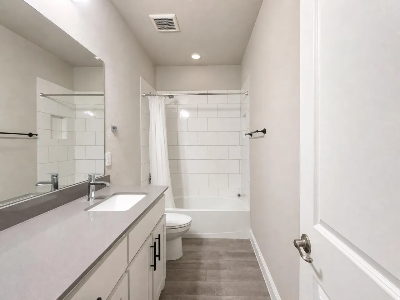 Bathroom featuring a single vanity with an integrated sink, polished chrome faucet, and gray countertop