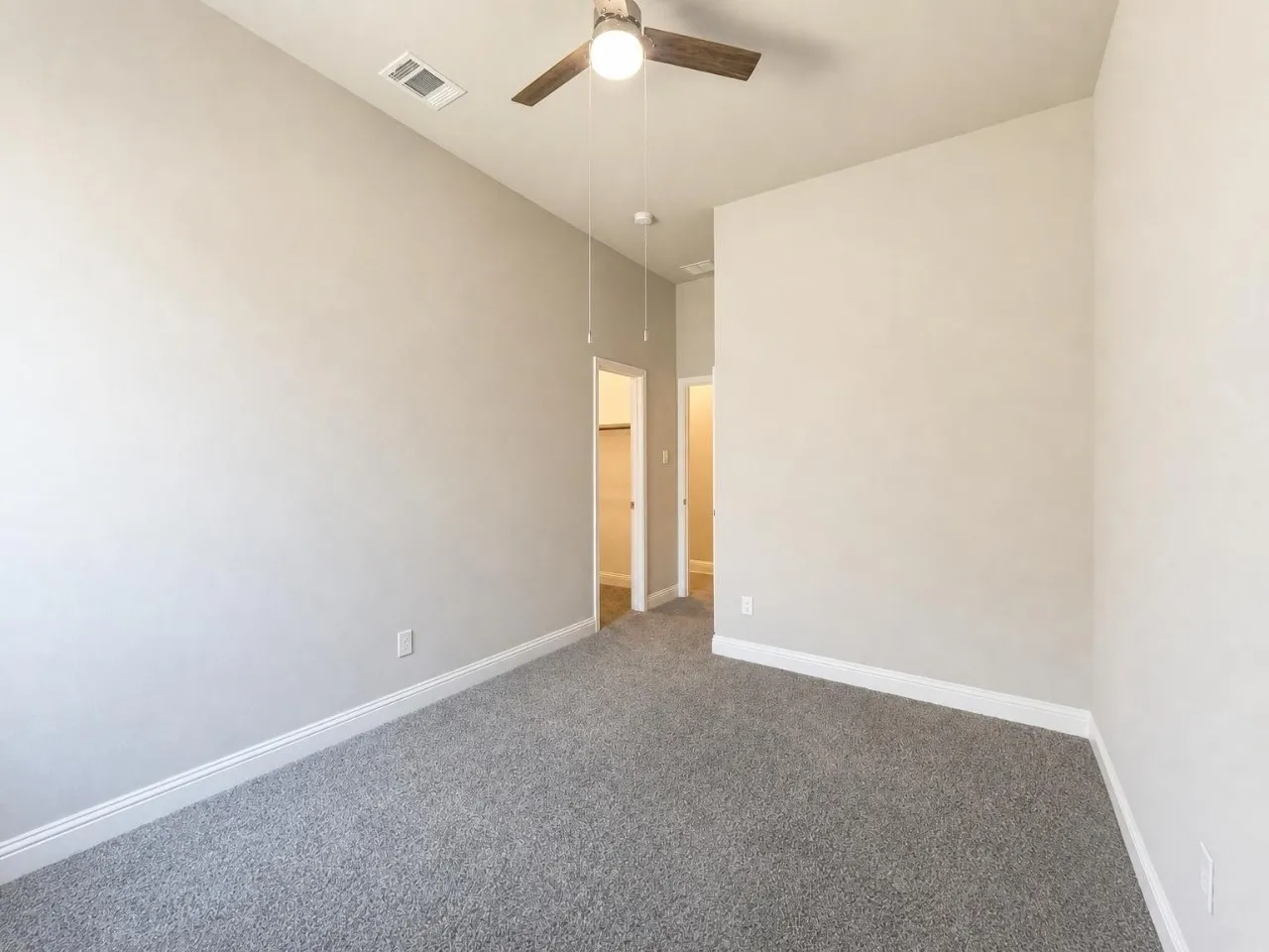 Neutral-toned walls complement plush grey carpeting