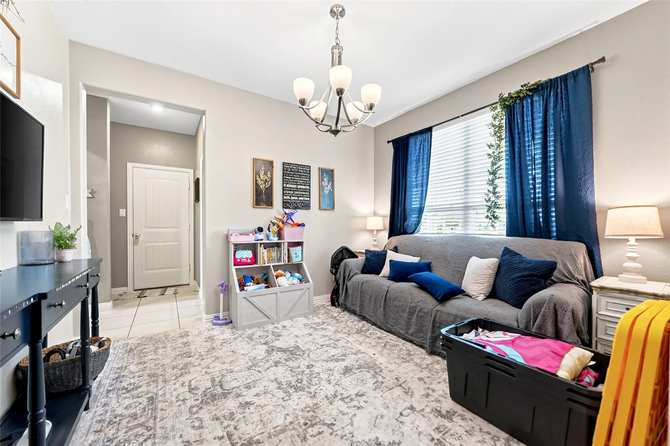 Recessed lighting, a hanging chandelier, and a window with blinds provide ample illumination