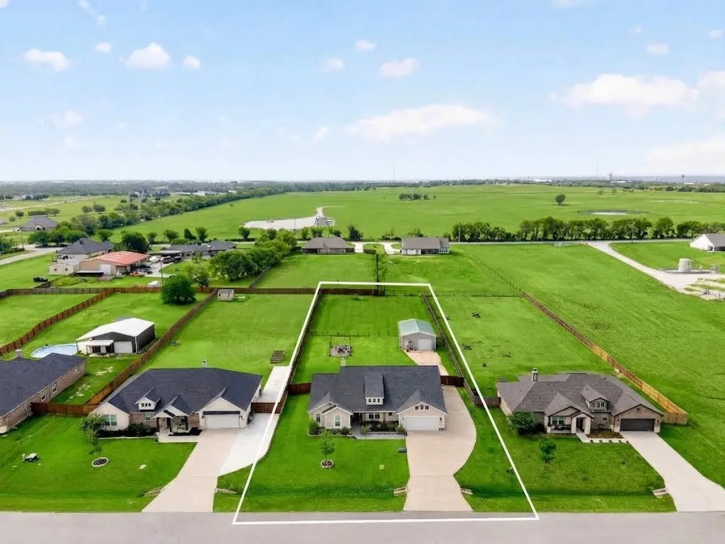 Expansive property featuring a single-story residence, a detached auxiliary structure, and a broad paved driveway