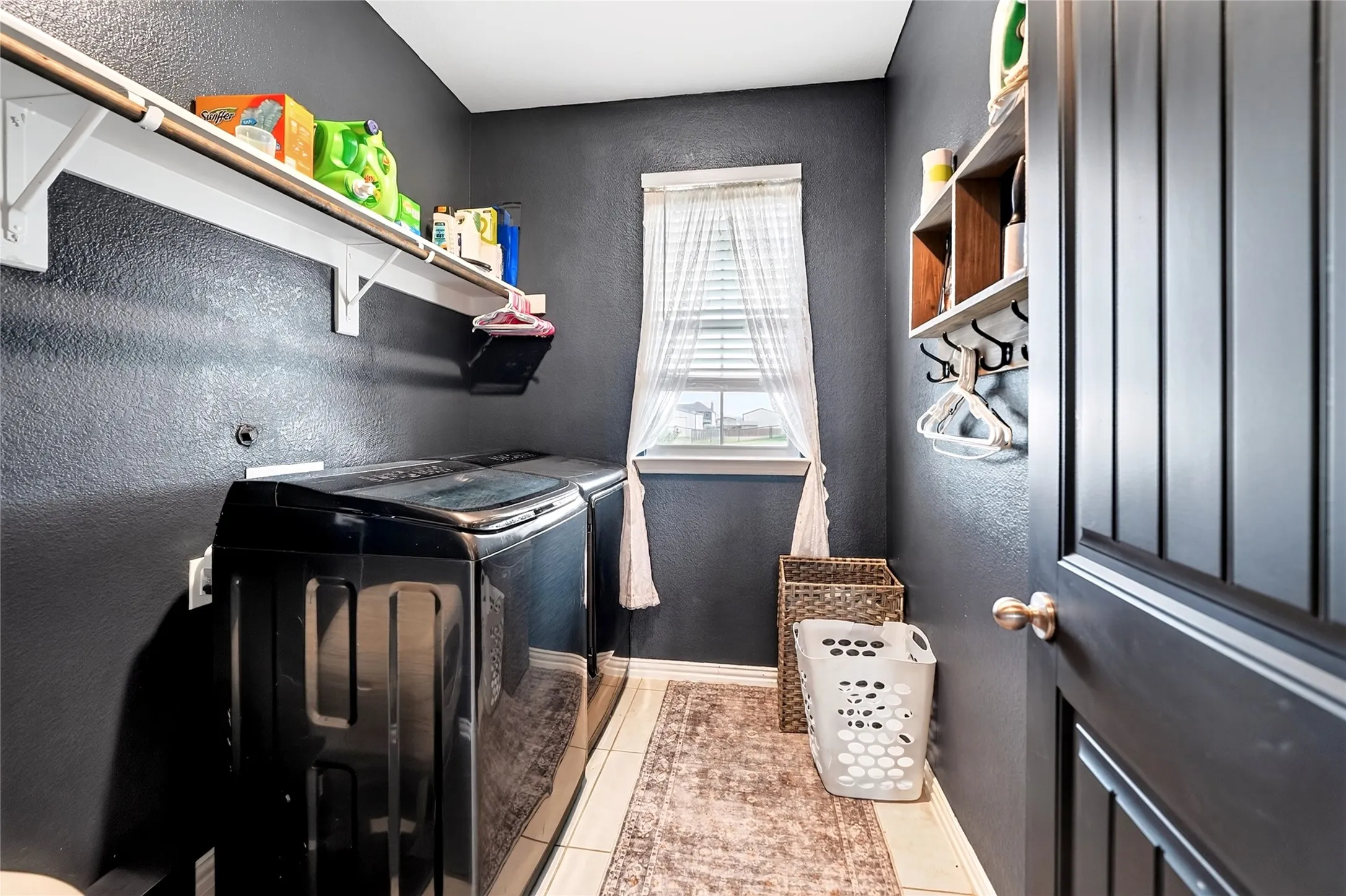 Built-in shelving with hanging rod, tile flooring, and wall-mounted storage with hooks