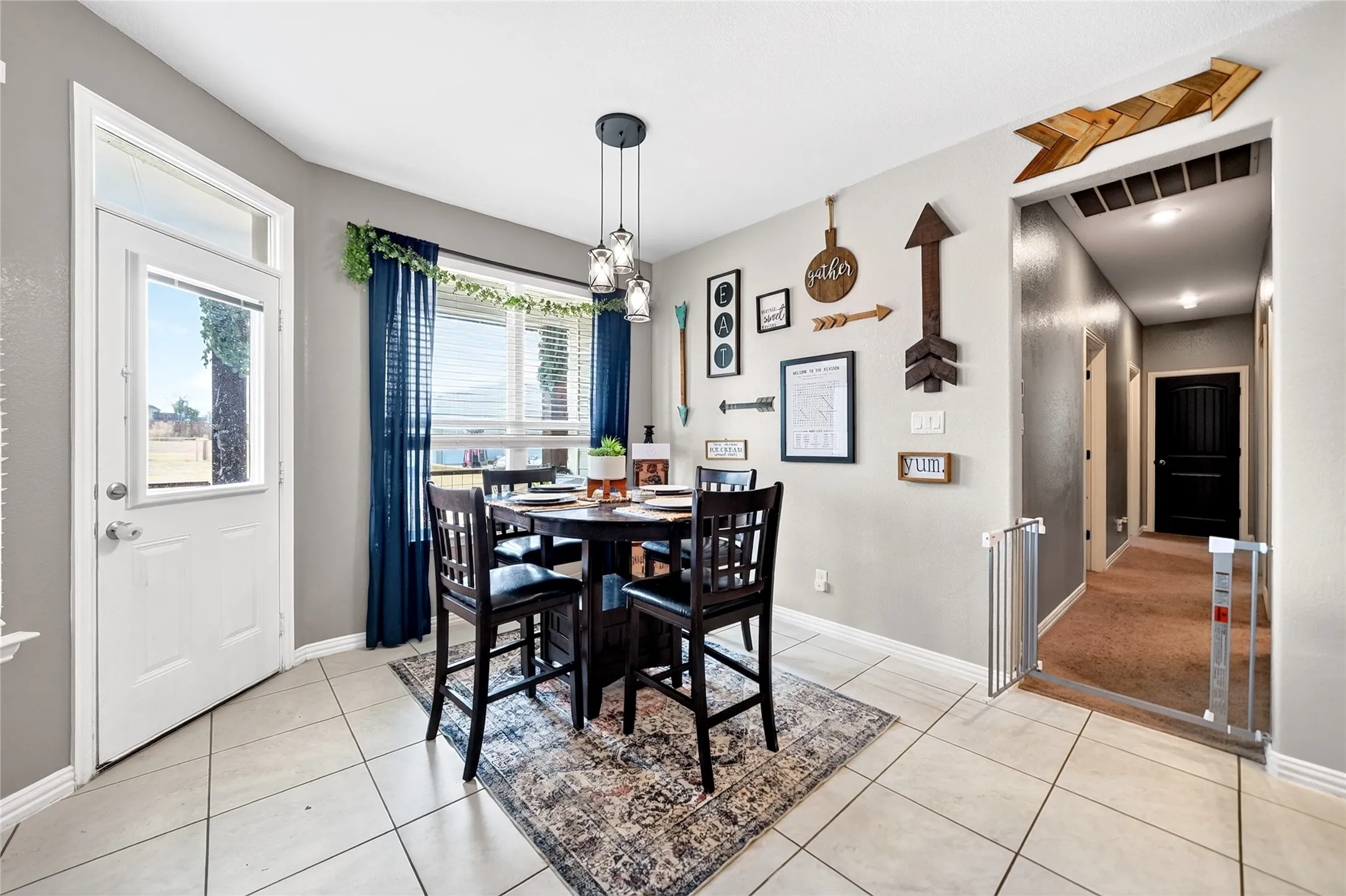 Tiled flooring extending into a dining area with a multi-light pendant fixture