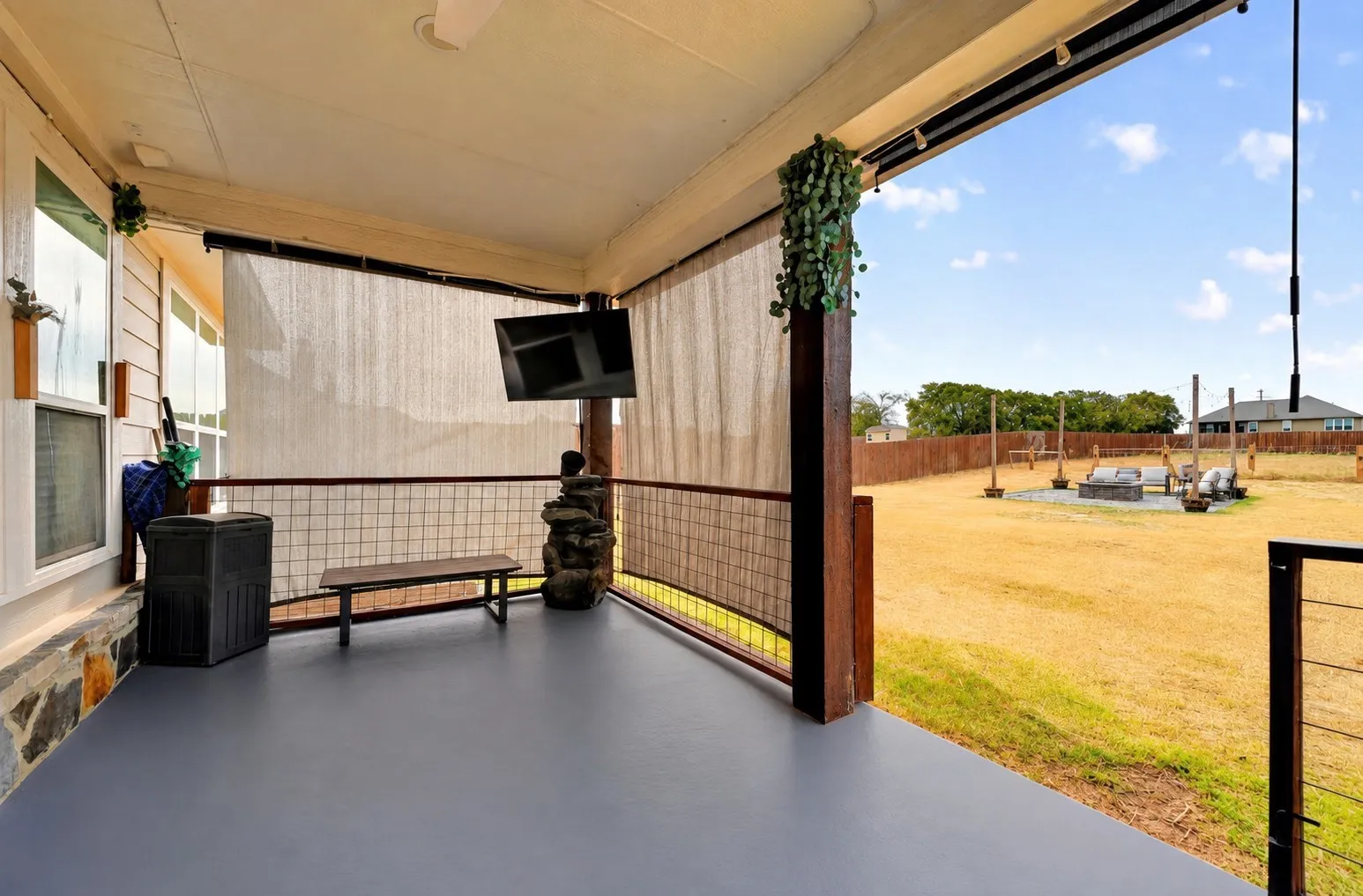 Covered patio with a durable floor finish, metal railing, and a mounted screen