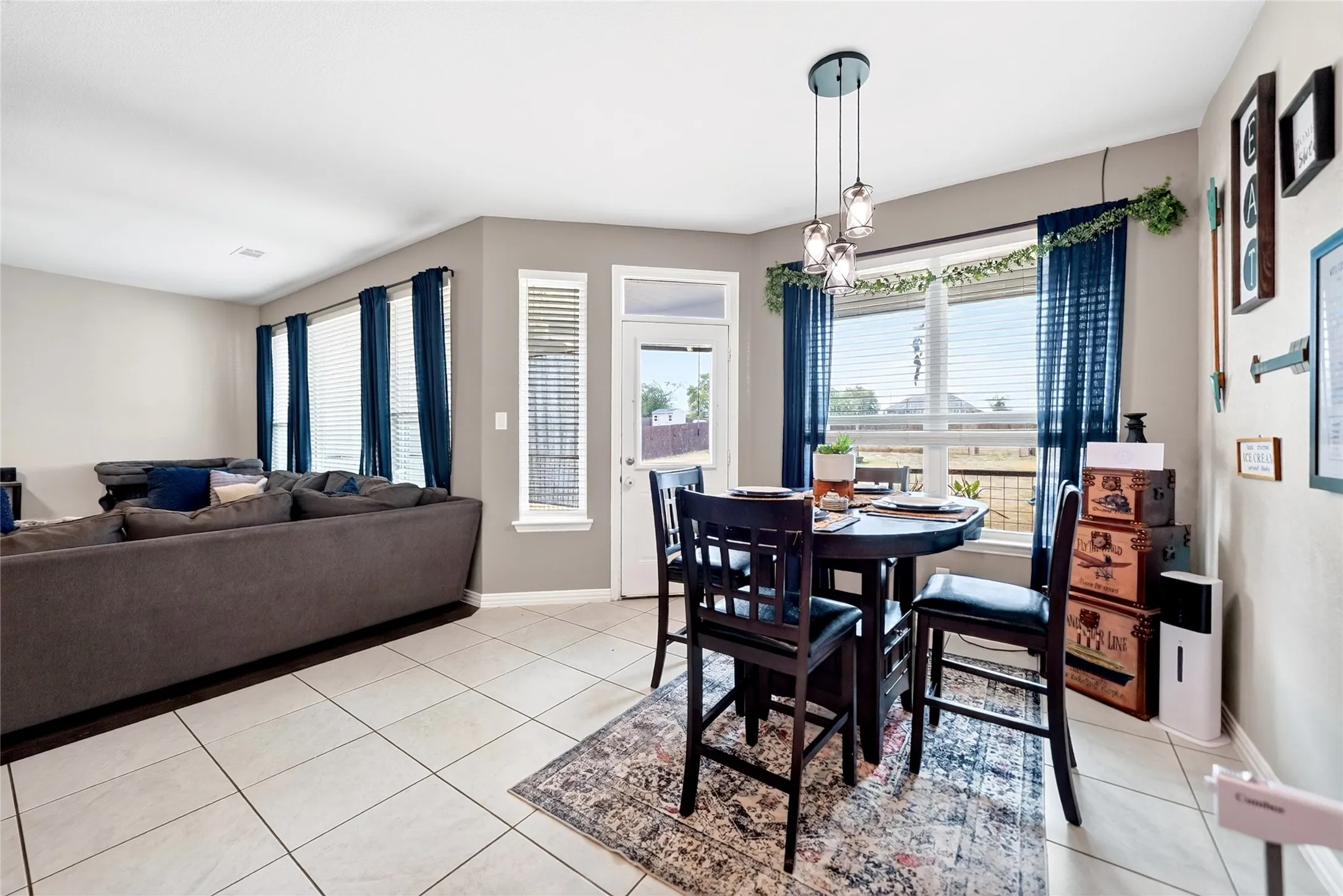 Open-concept living space with tile flooring, multiple windows, and a built-in light fixture