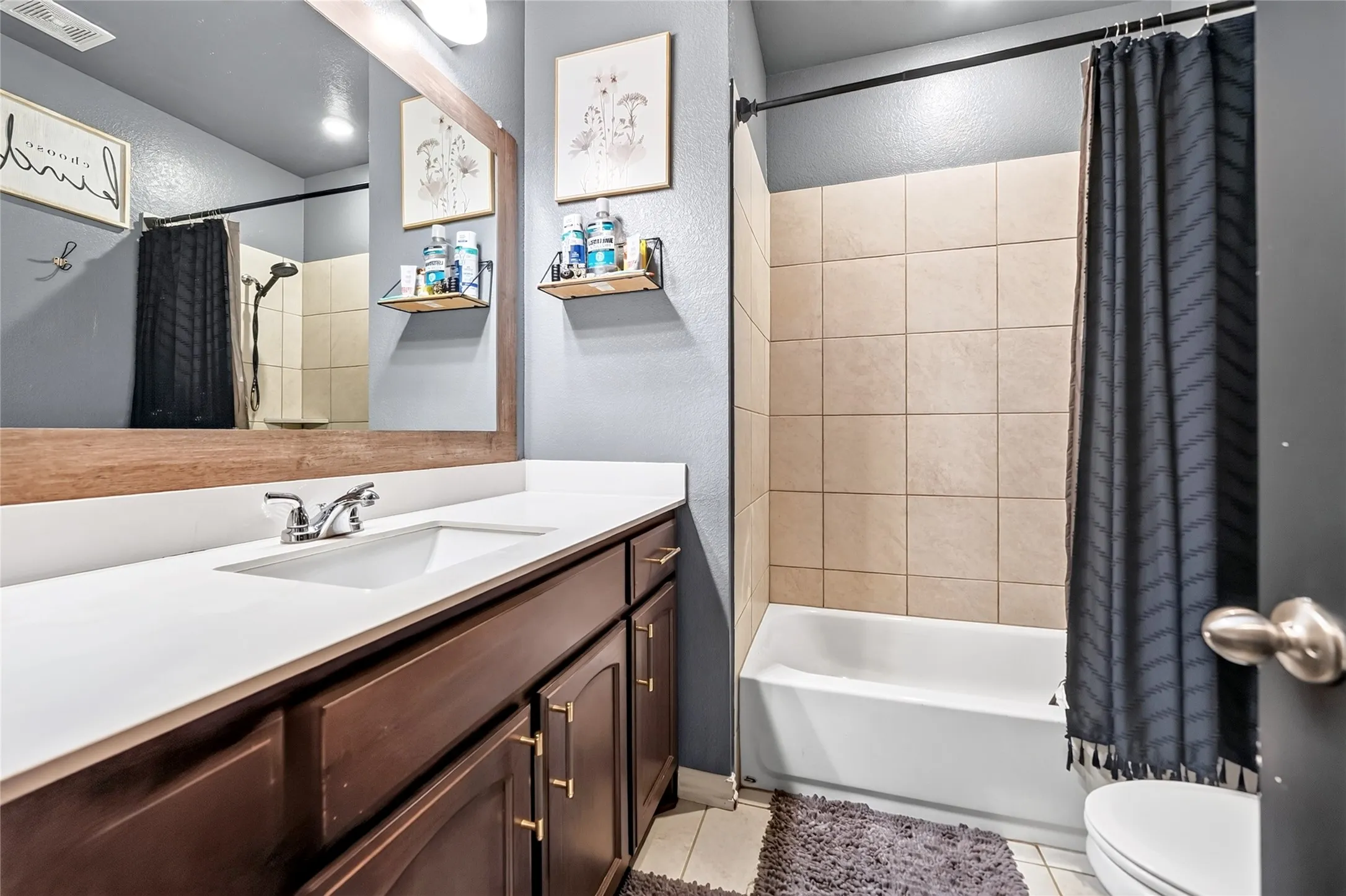 Bathroom featuring a wood-finish vanity with an integrated sink and a white countertop