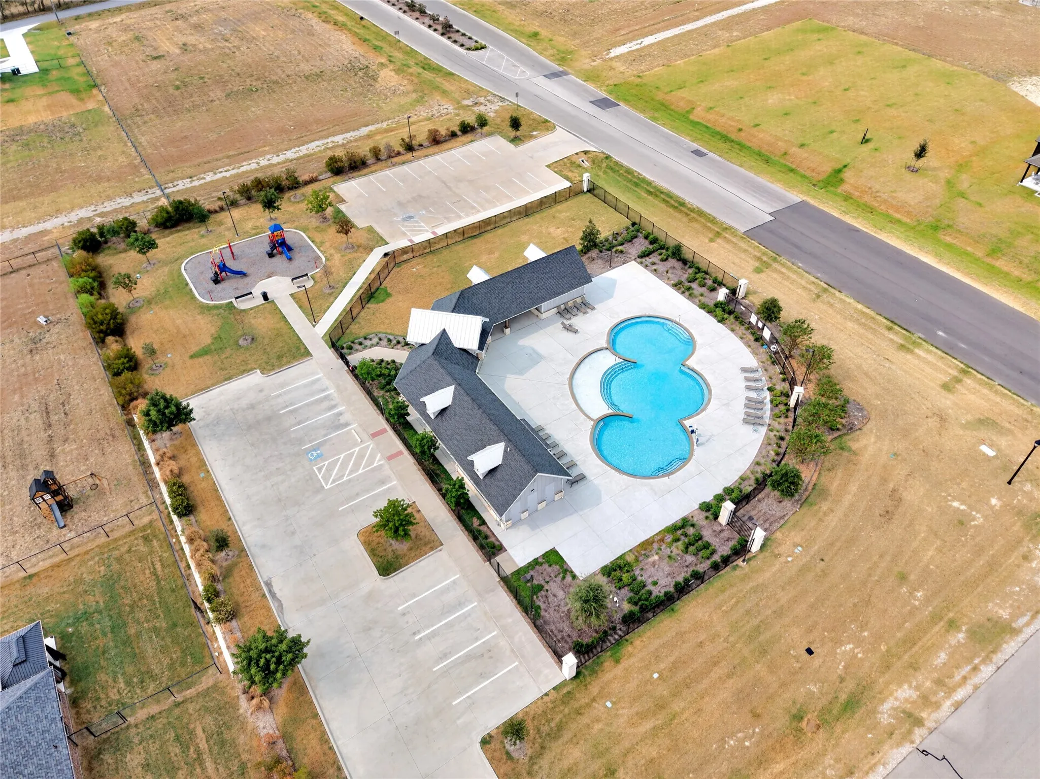 Community swimming pool with sun lounge area, adjacent clubhouse, and a dedicated parking lot