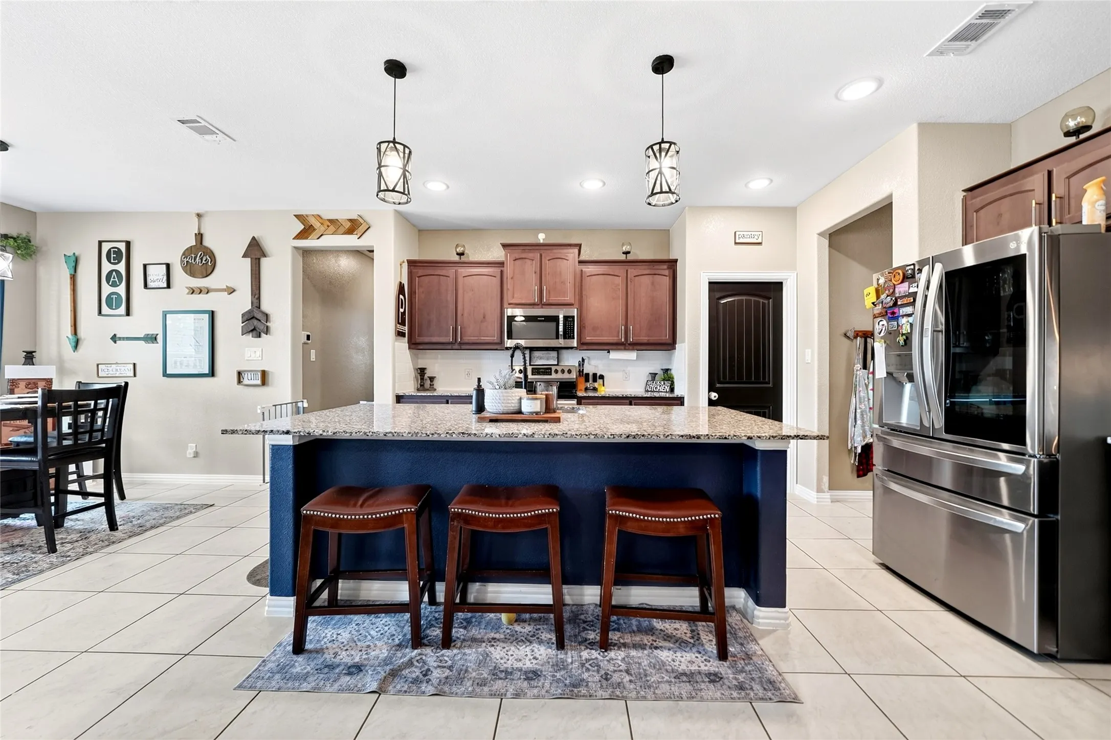 Kitchen featuring an expansive island with a granite countertop, wood-finish cabinetry, and stainless steel appliances