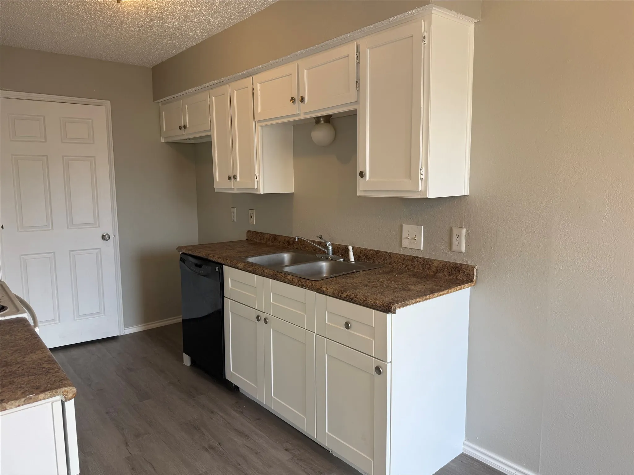 White cabinetry with silver hardware, dual basin stainless steel sink, wood-finish flooring, and a built-in dishwasher