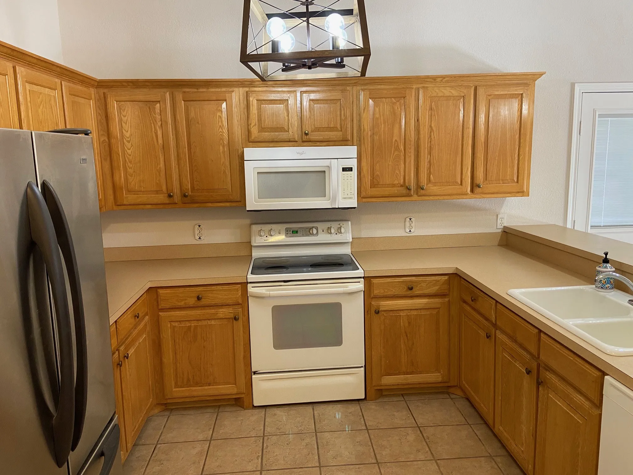 Kitchen with view of the fridge, microwave, stove.