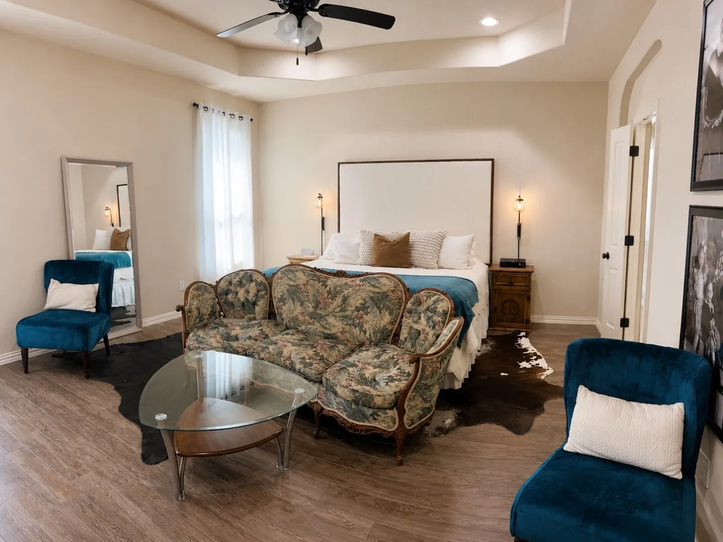 Tray ceiling with recessed lighting, wood-finish flooring, full-height window with sheer curtains, solid core door with black hardware, and built-in ceiling fan with light fixture