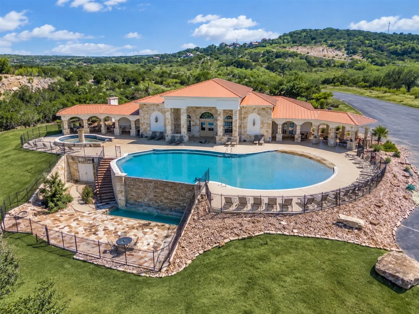 Resort-style pool with a curved edge, adjacent spa, and a stone-clad exterior