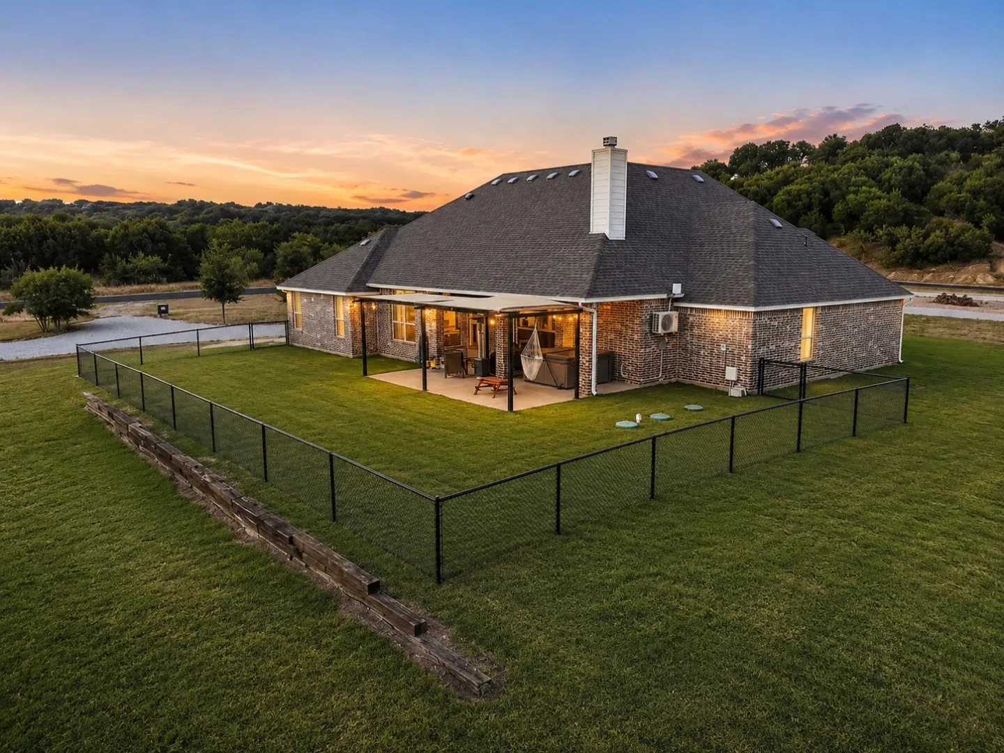 Expansive backyard featuring a manicured lawn, complete perimeter fencing, and a covered patio with recessed lighting
