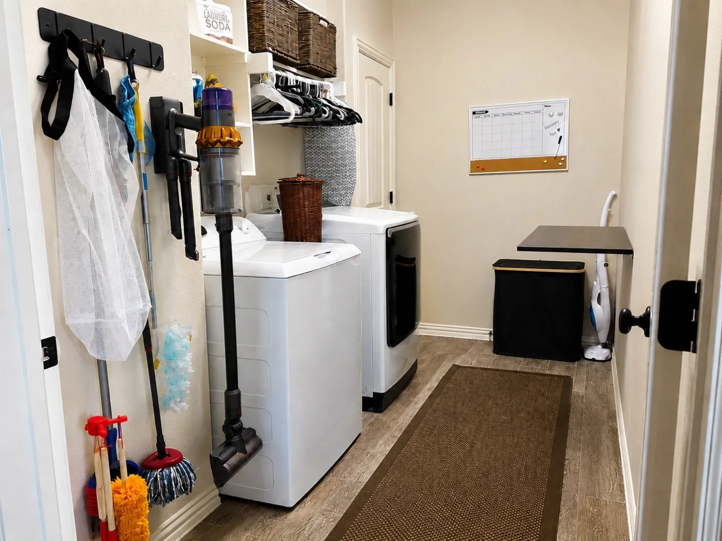 Laundry room featuring built-in shelving, a wall-mounted drying rack, and wood-finish flooring