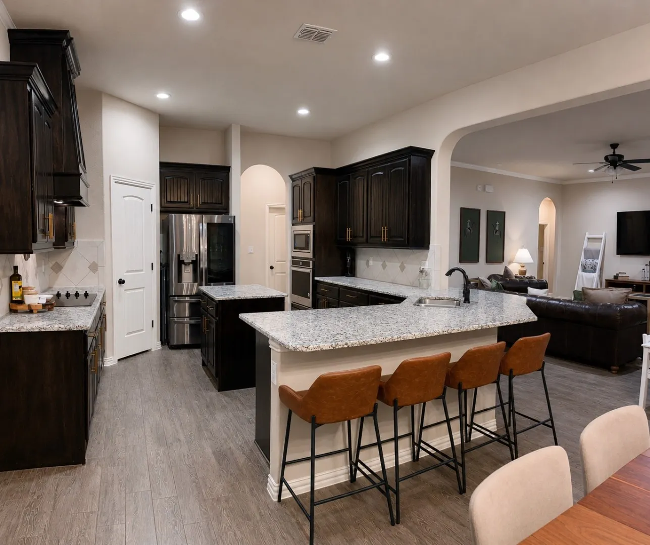 Kitchen featuring dark wood-finish cabinetry, light-toned countertops, two central islands, and stainless steel appliances