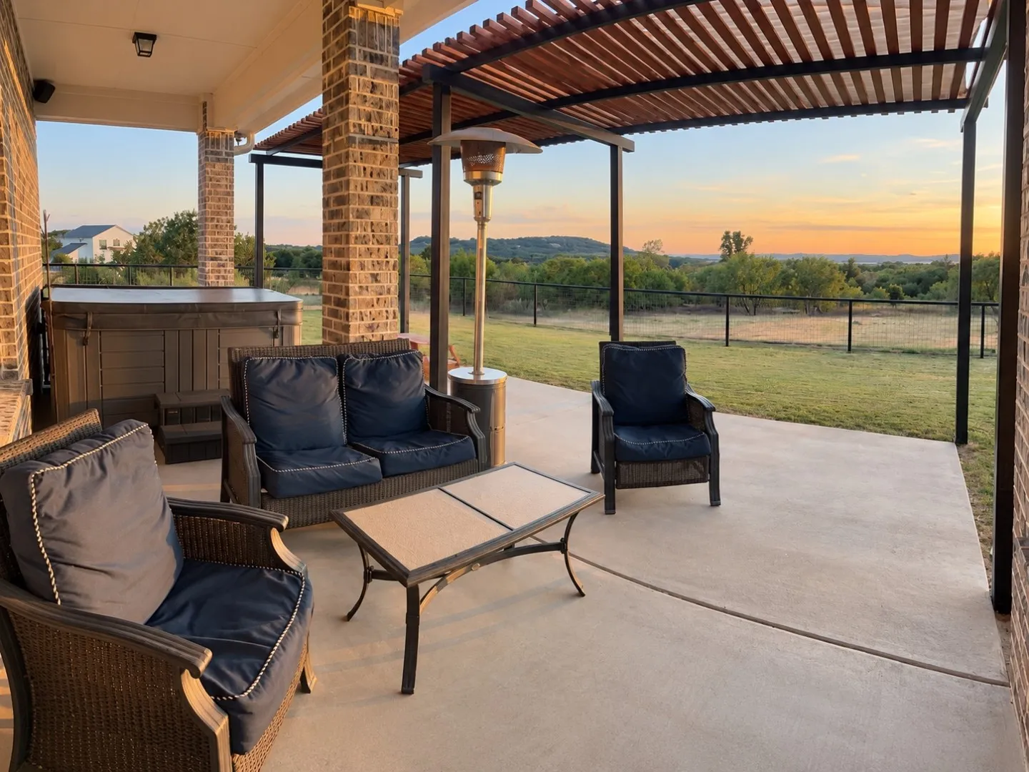 Expansive covered patio with brick columns, wood-slat pergola, and a built-in spa