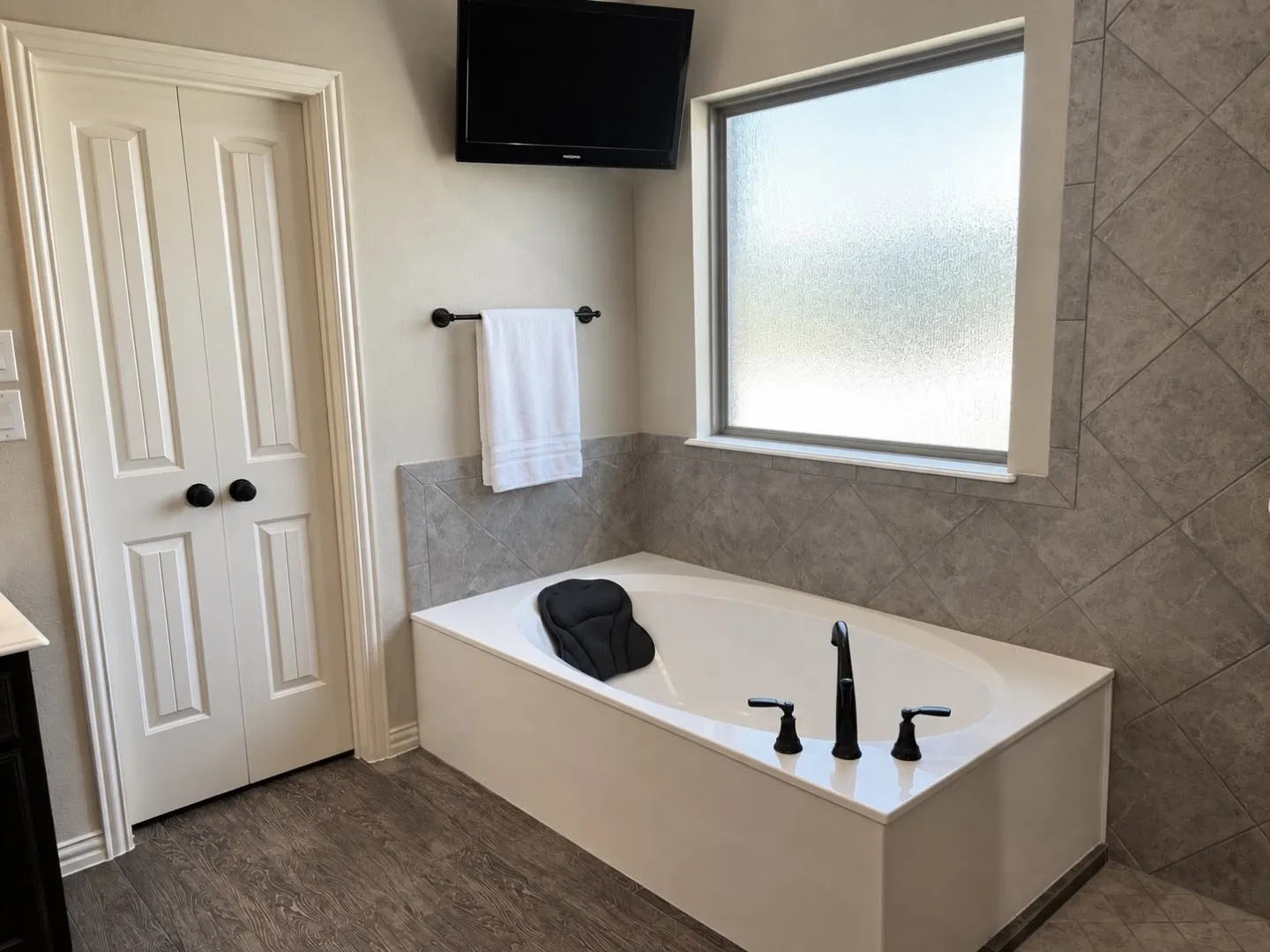 Built-in soaking tub with matte black fixtures, set against diagonal tile wainscoting