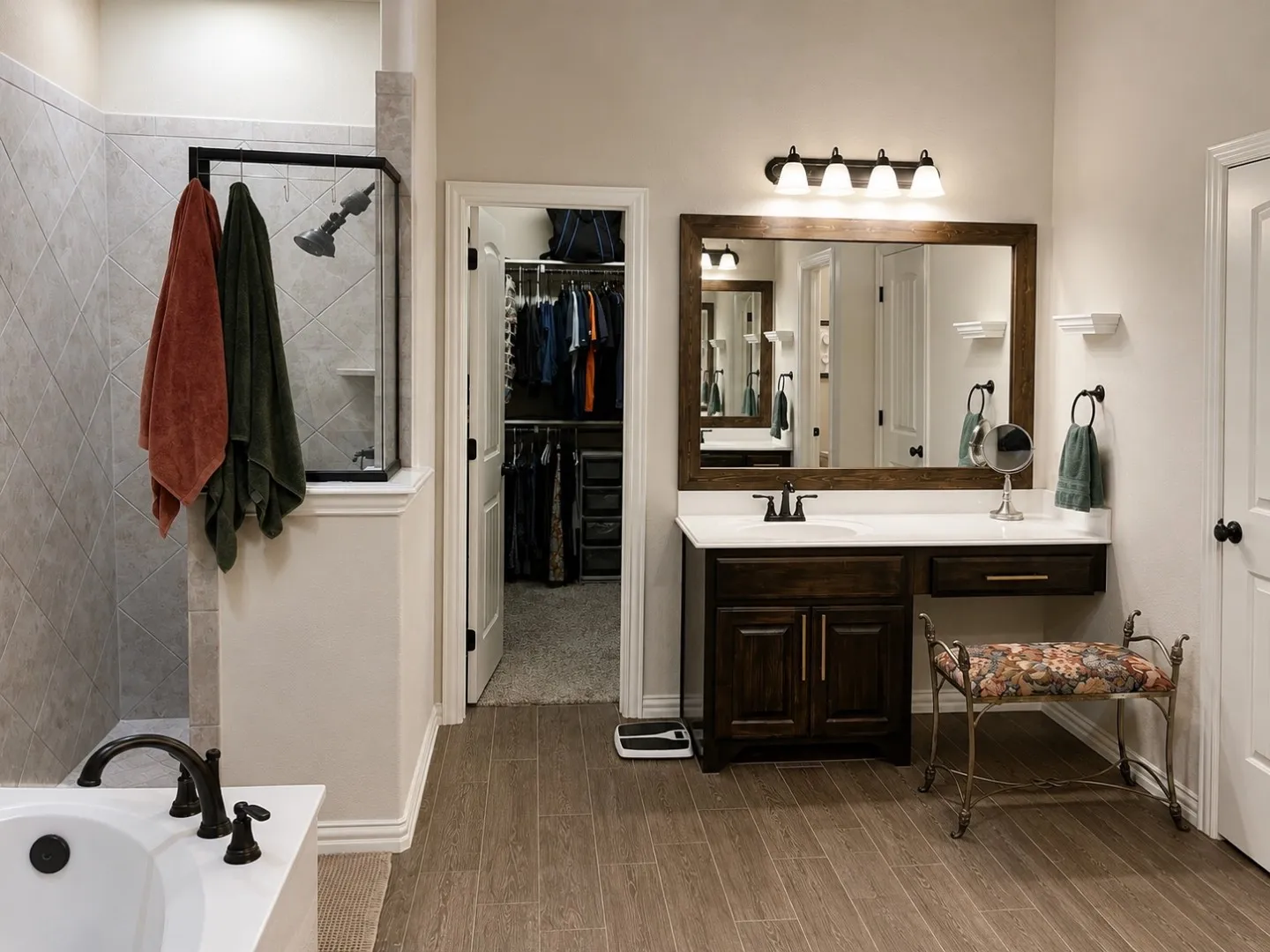 White countertop vanity with a dark wood-finish cabinet and integrated sink, framed mirror, and wood-finish flooring