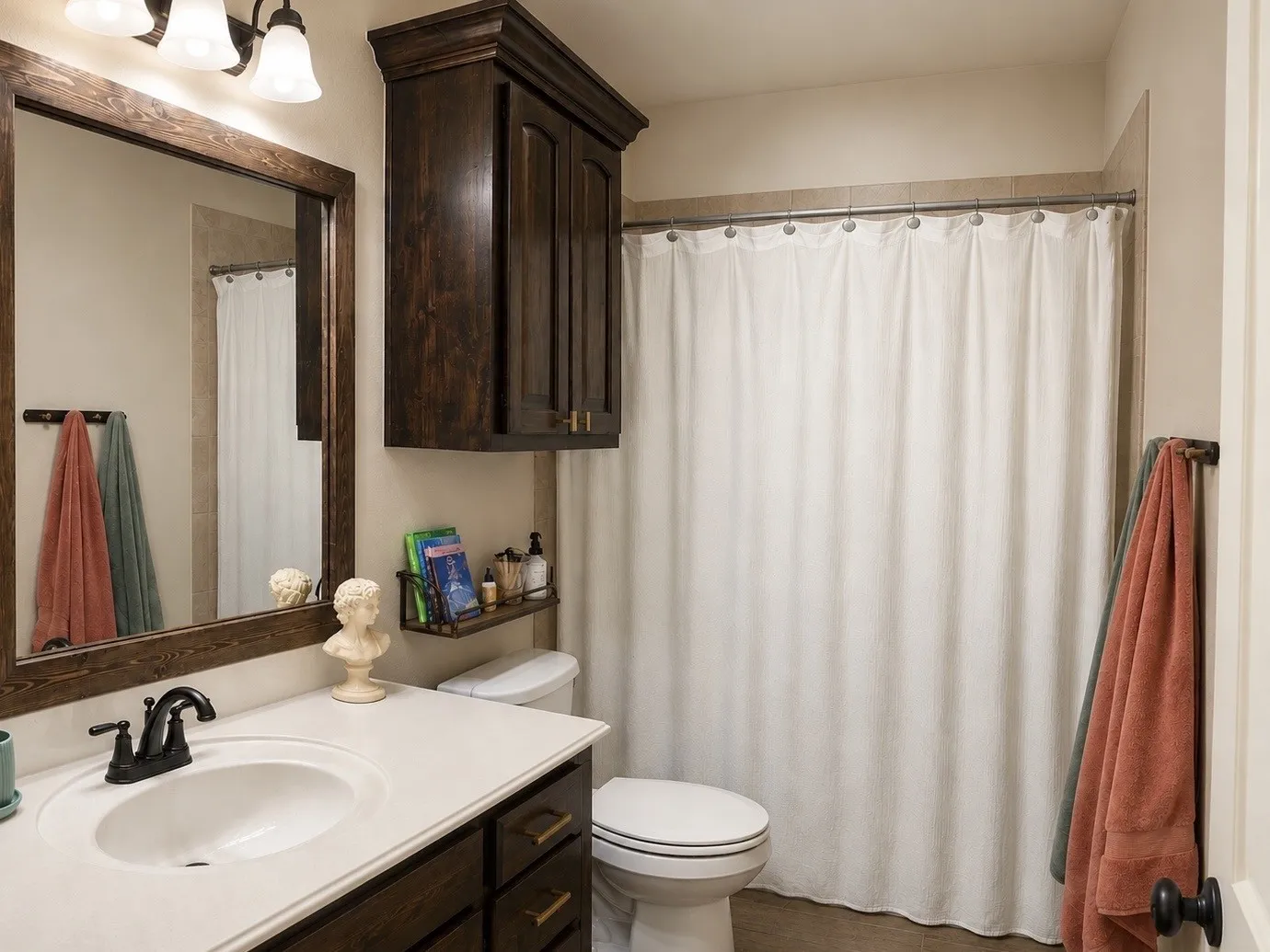Vanity with white countertop and integrated sink, dark wood-finish cabinet with brass hardware, framed mirror, and coordinating wall-mounted cabinetry