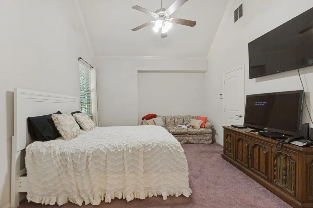 Vaulted ceiling with ceiling fan, window with blinds, and wall-to-wall carpeting.