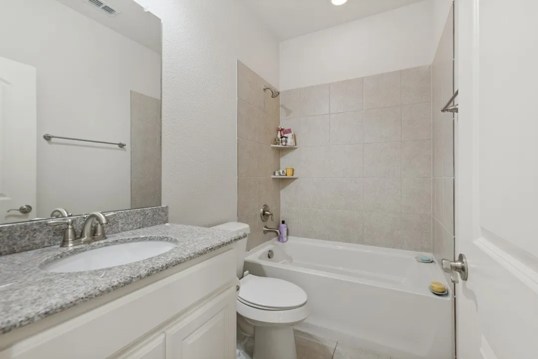 This guest bathroom features a bright, clean design highlighted by a crisp white vanity cabinet topped with elegant, durable granite countertops, offering a modern and inviting aesthetic for visitors.