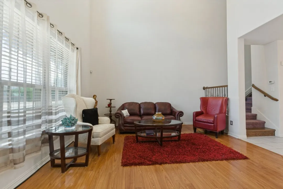 High ceilings enhance the spacious living area featuring wood-finish flooring and large windows