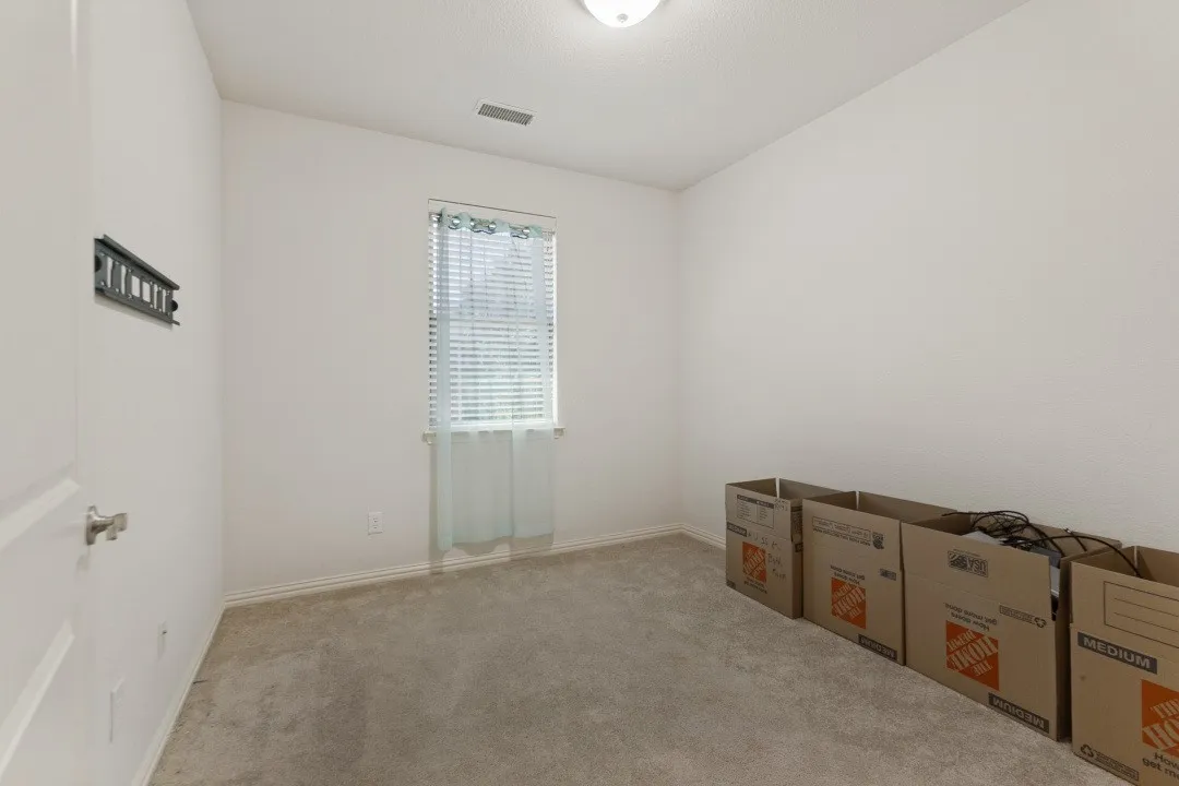 Neutral-toned wall finishes, light-toned carpeting, and a window with blinds provide a neutral foundation