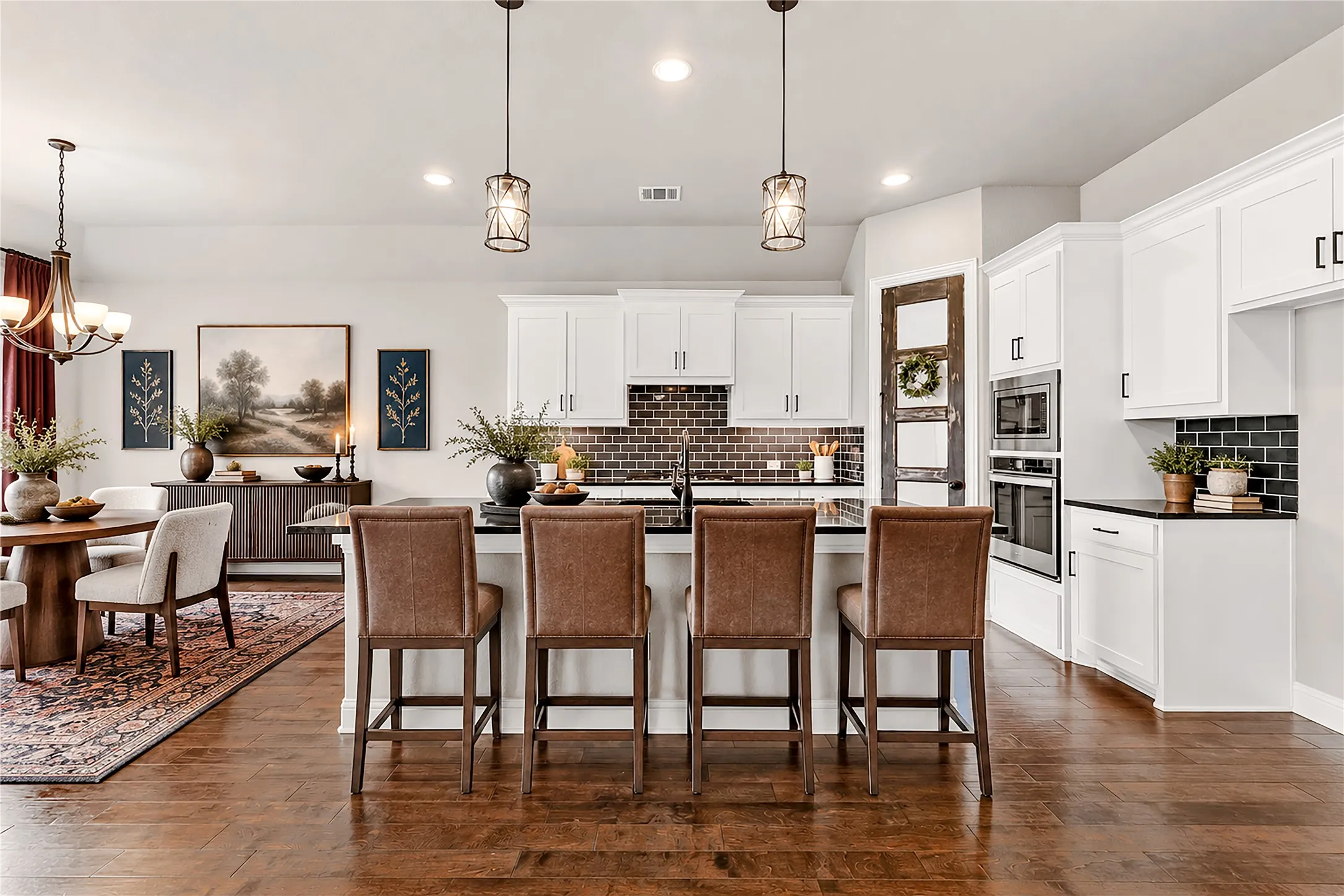 Kitchen featuring an island with built-in cabinetry, dark countertops, white upper and lower cabinetry, and a subway tile backsplash. Virtual staged.