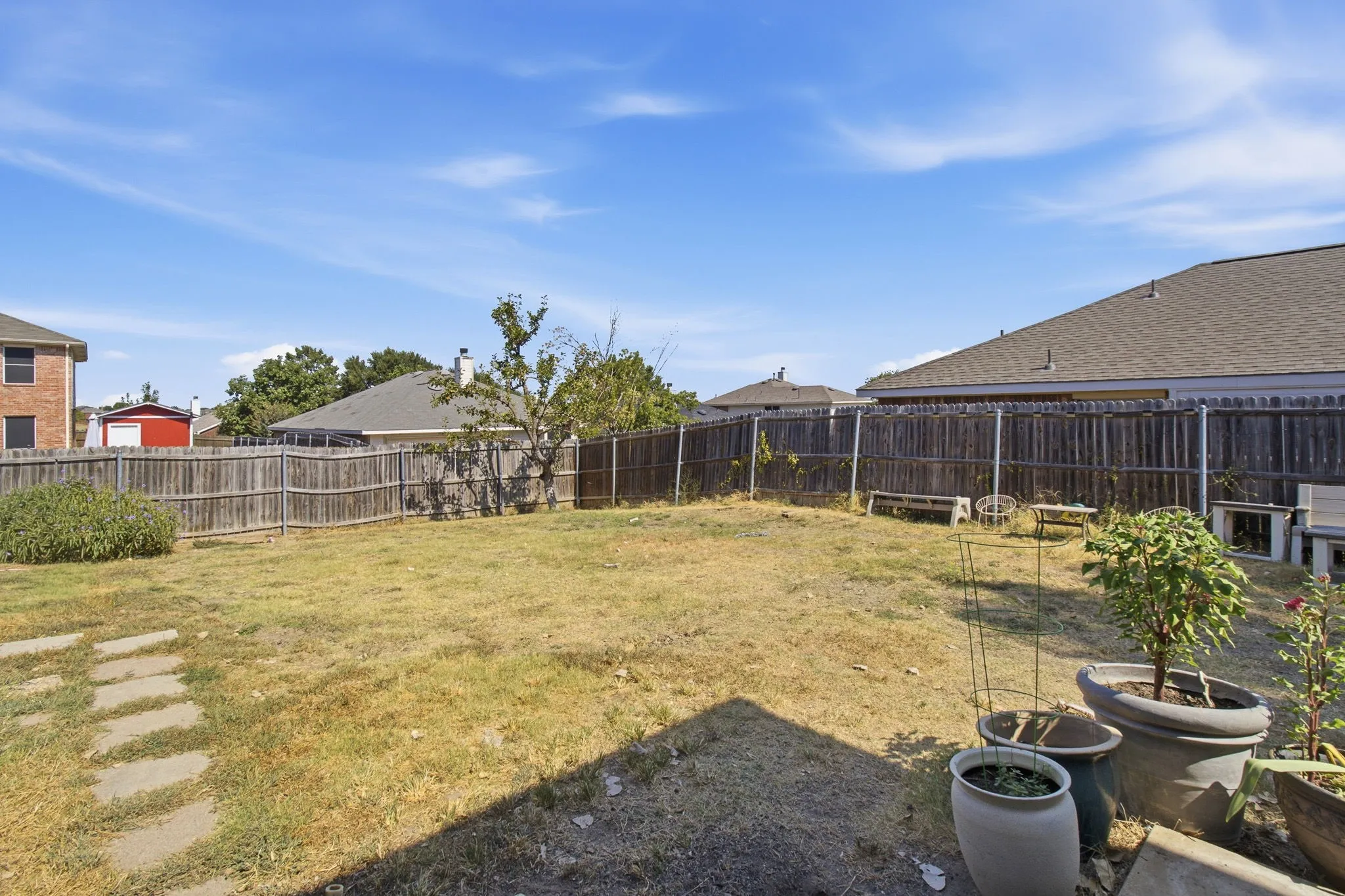 Expansive backyard featuring a wood fence perimeter and a stepping stone path