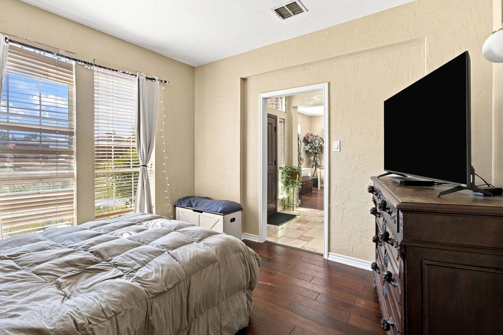 Wood-finish flooring, multiple windows with blinds, and neutral wall tones