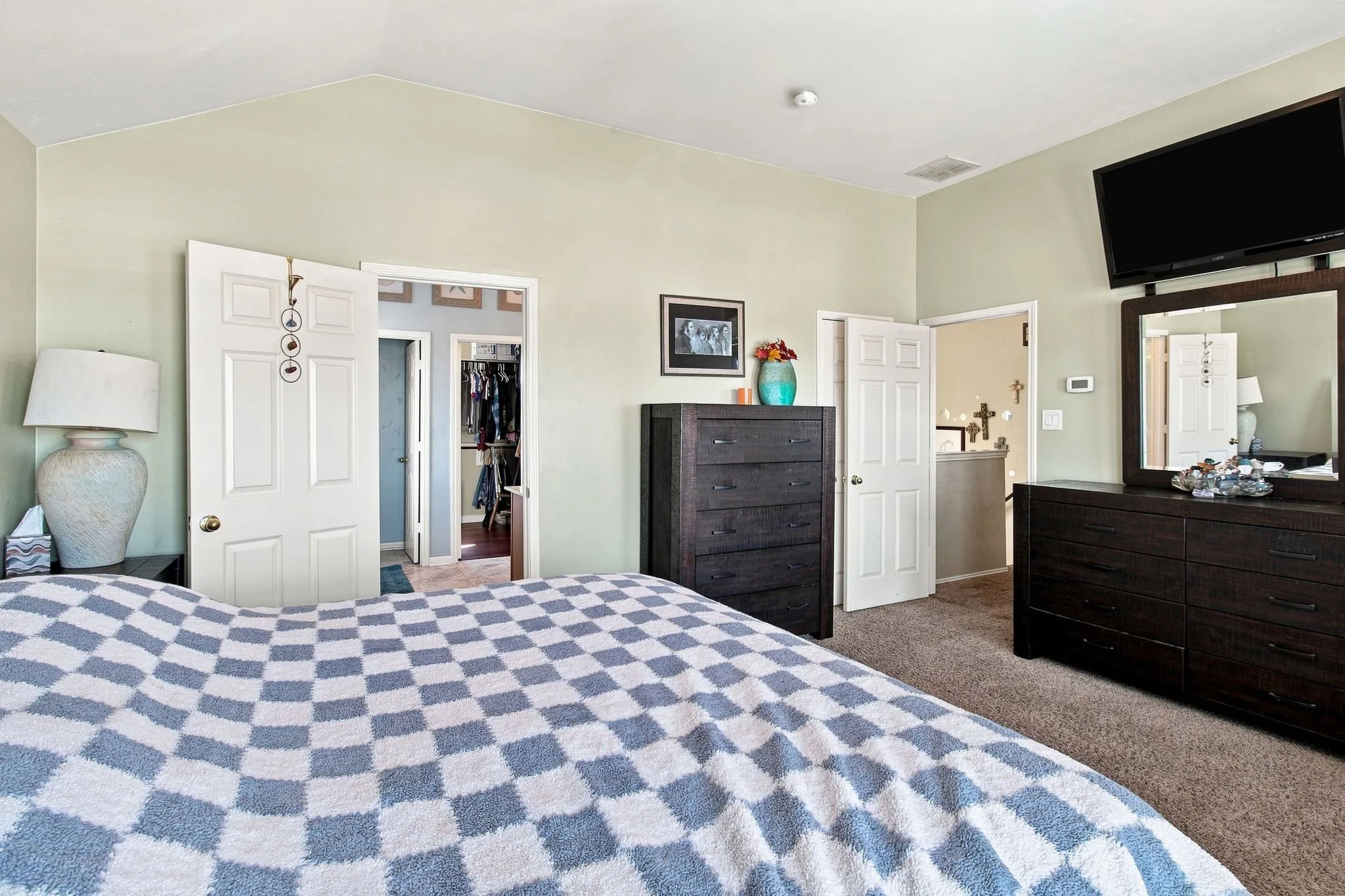 Vaulted ceiling with light-toned walls, carpeted flooring, and white paneled doors