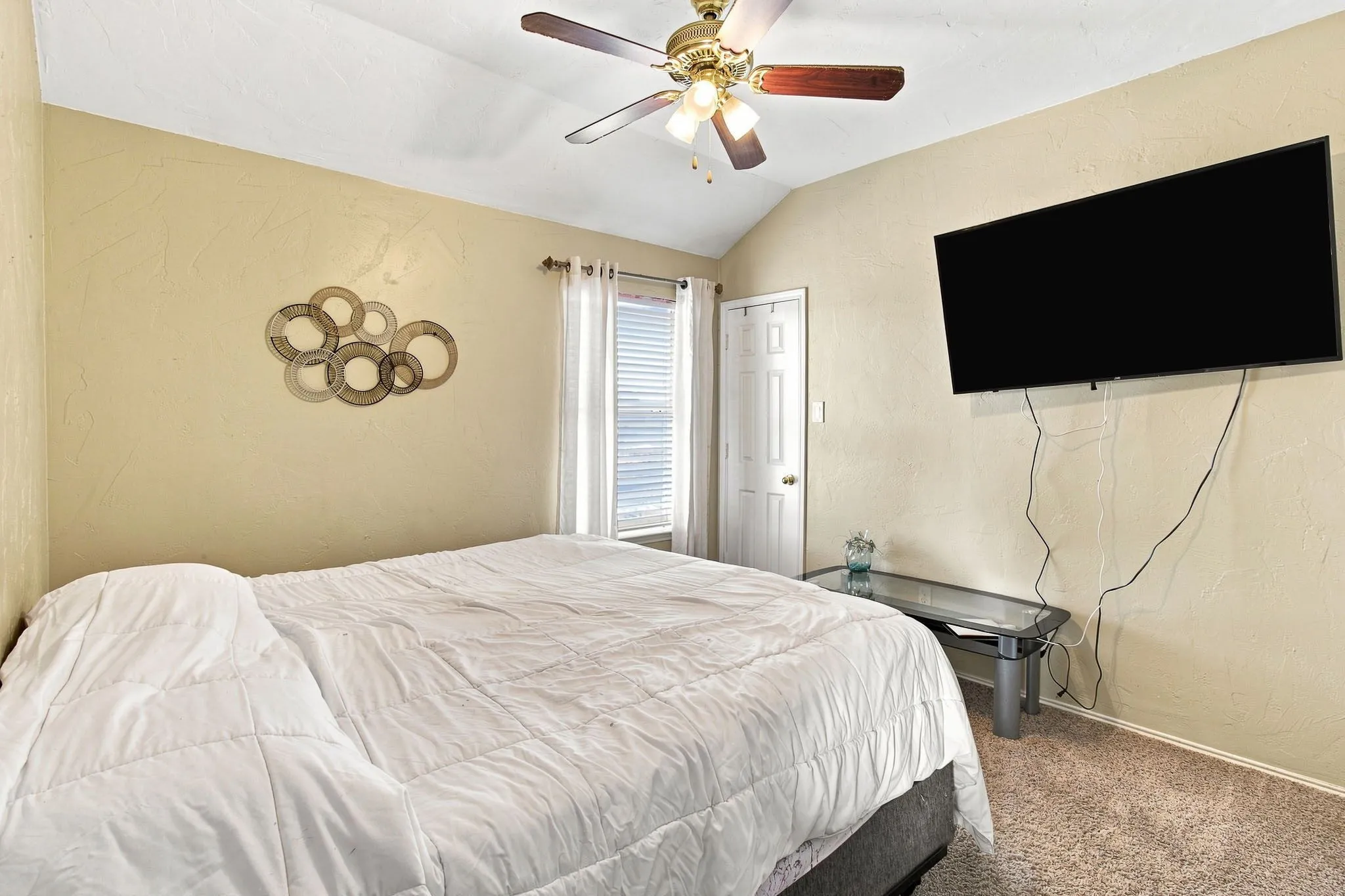 Vaulted ceiling with a ceiling fan, textured walls, window with blinds and drapes, and carpeted flooring