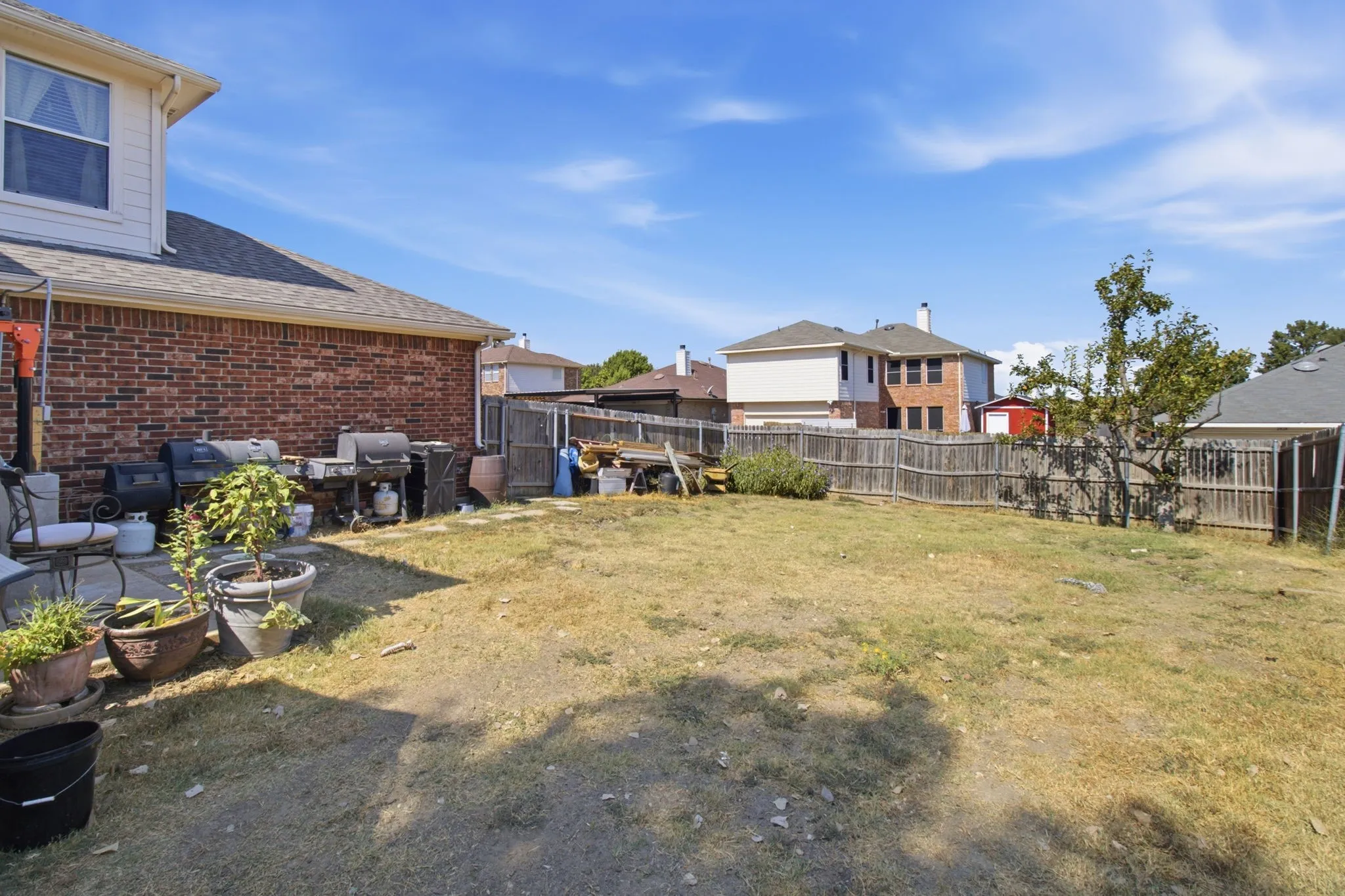 Expansive backyard with a wood privacy fence, brick exterior, and a stone patio